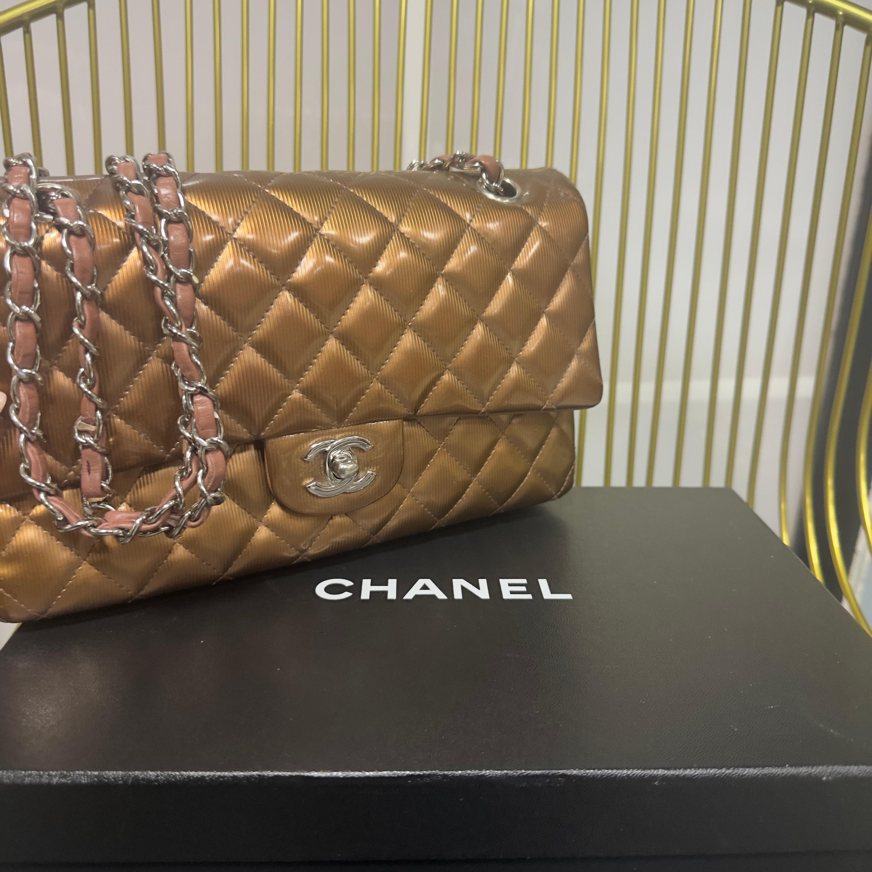 Sac à rabat classique iconique de Chanel en tissu satiné métallisé bronze avec finition matelassée et fermeture à verrou CC en métal argenté.
L'intérieur en cuir souple rose poudré est doté d'un double rabat avec le logo Chanel embossé et d'une