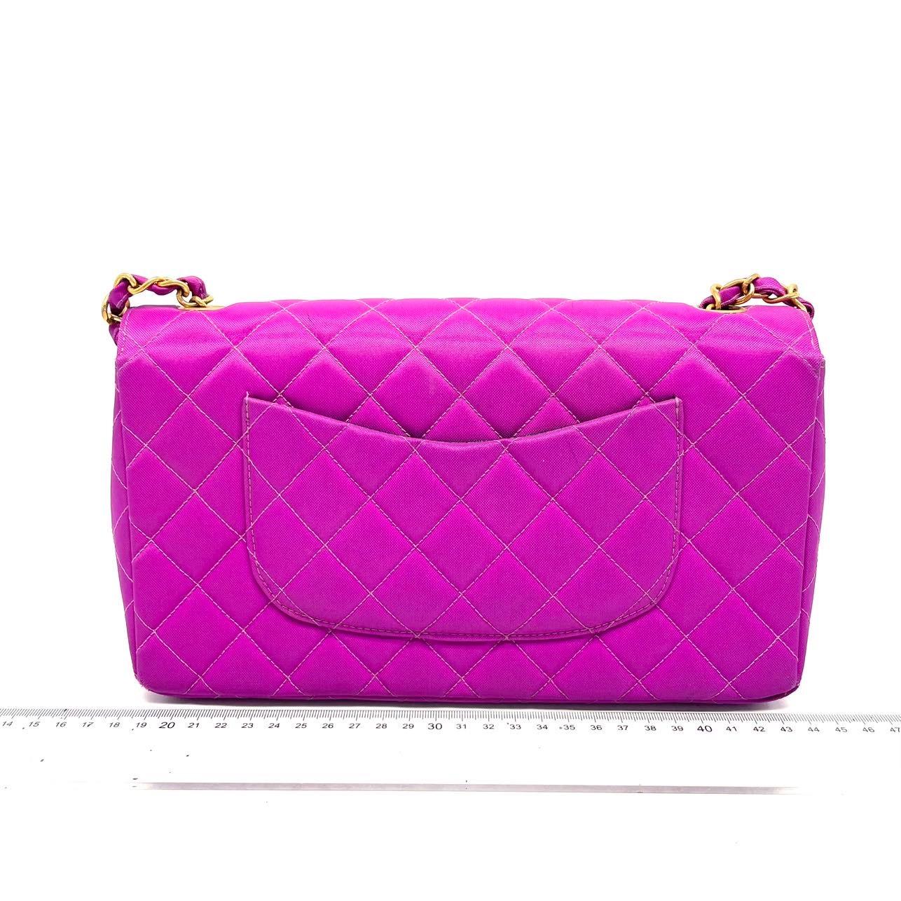 This one-of-a-kind Chanel Classic Flap Vintage bag is sure to grab attention in a crowd! Crafted from light and durable canvas, it is adorned with 24k gold hardware which dazzles in the rare stunning fiery pink. Truly a collector's item.