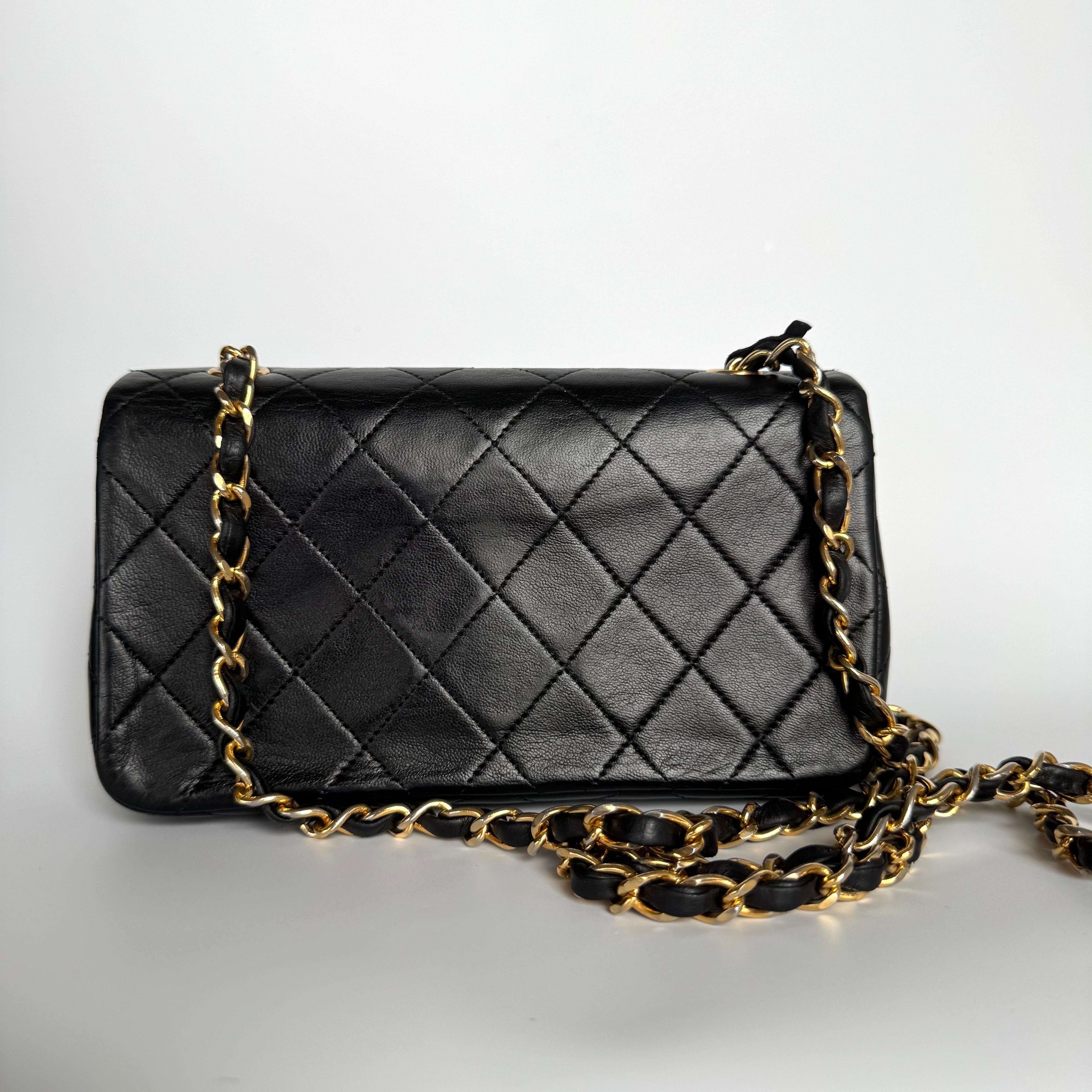 Diese einmalige Chanel Classic Flap Vintage Tasche strahlt Raffinesse und zeitlose Eleganz aus. Sie ist aus luxuriösem schwarzem Lammleder gefertigt und mit 24-karätigen Goldbeschlägen verziert. Die zwischen 1989 und 1991 hergestellte Tasche ist