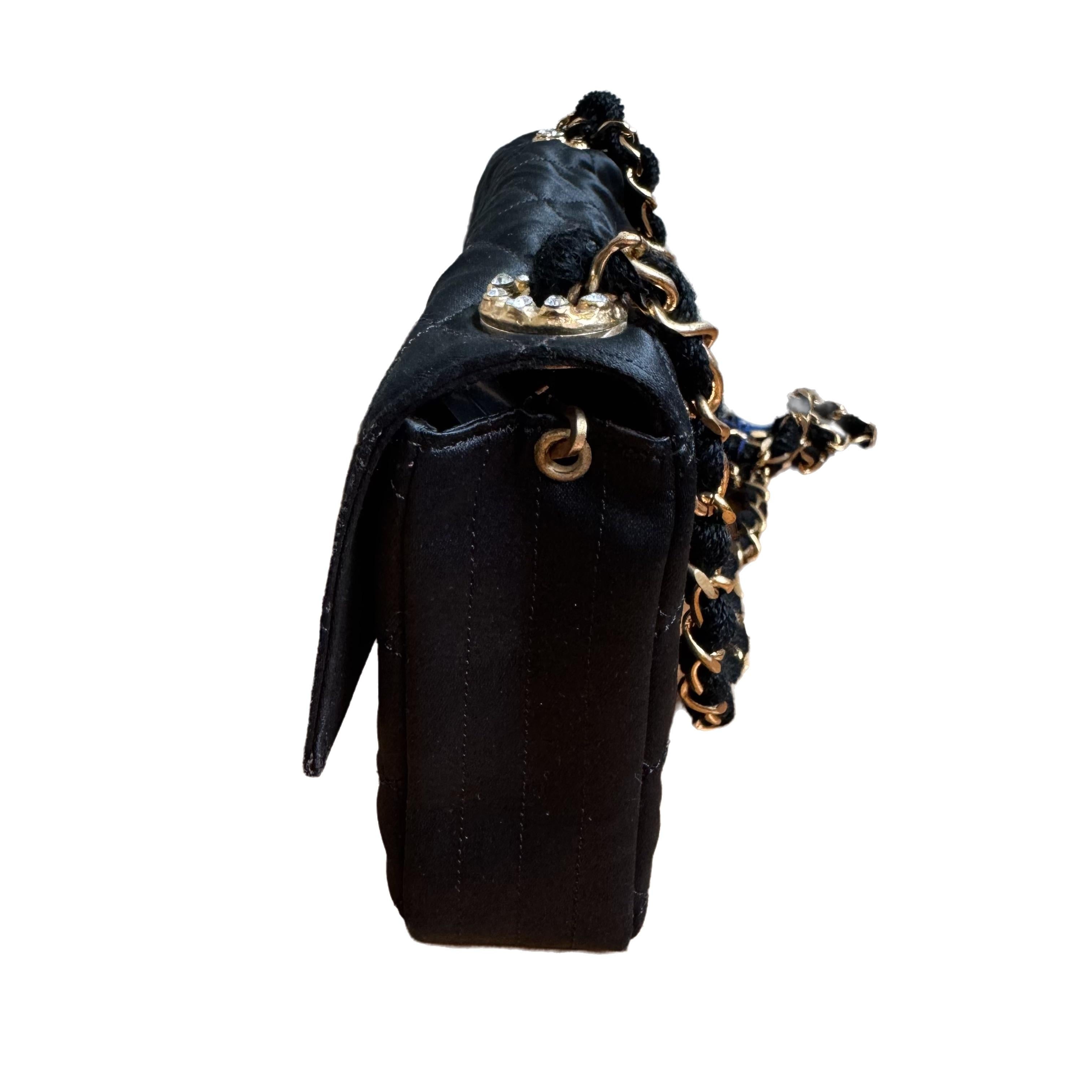 This one-of-a-kind Chanel Classic Flap Vintage bag exudes sophistication and timeless elegance. Crafted from luxurious black silk, it is adorned with gems studded CC buckle.  This bag is truly a piece of luxury worth cherishing. The long strap