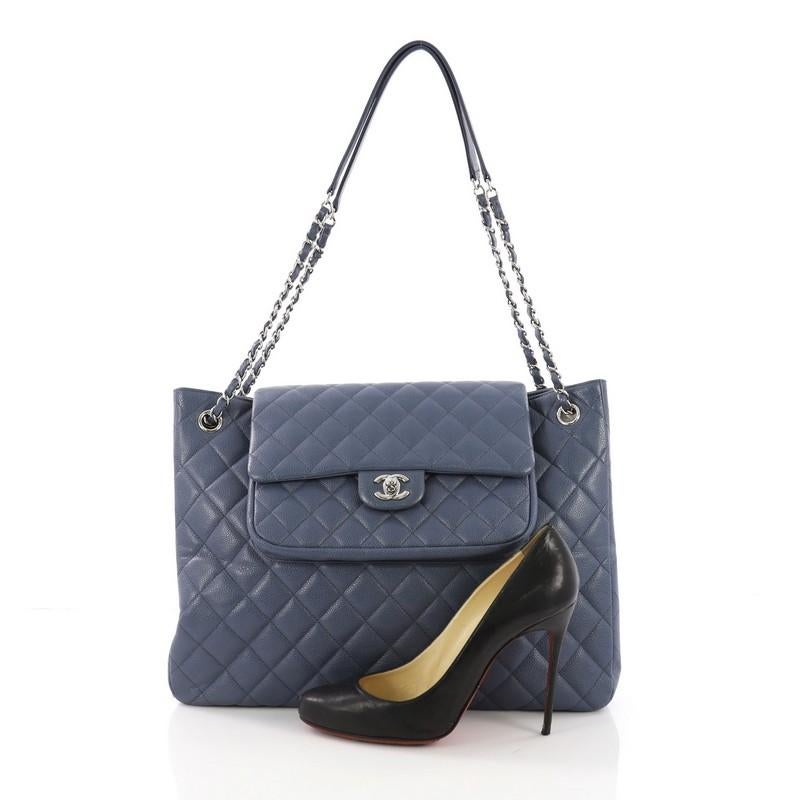This Chanel Classic Flap Shopping Tote Quilted Caviar Large, crafted in blue quilted caviar leather, features woven-in leather chain straps with leather pads, exterior back slip pocket, protective base studs, and silver-tone hardware. Its flap tab