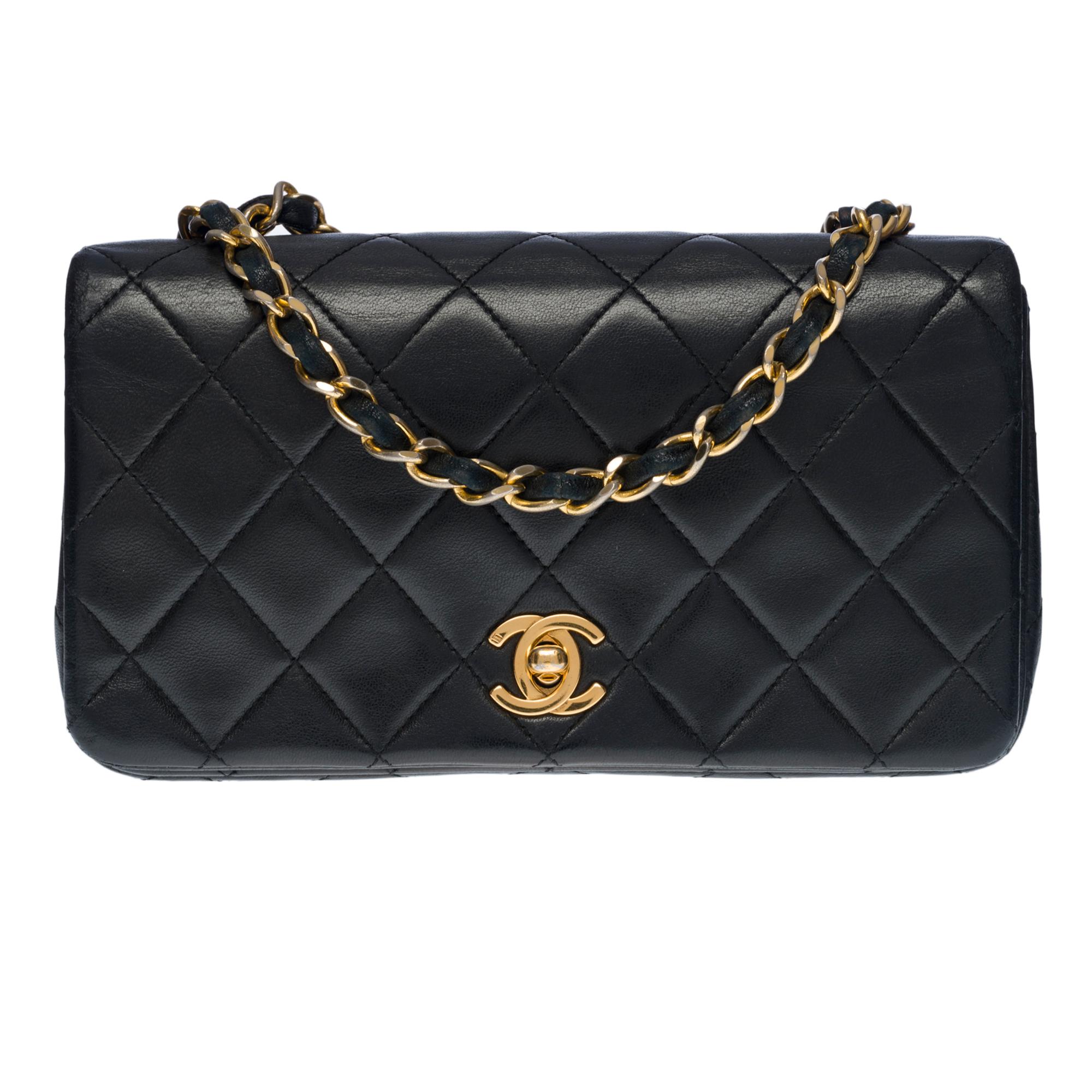 Charming Chanel Classic Mini Full Flap shoulder bag in black quilted lambskin, gold-tone metal hardware, a gold-tone metal chain handle interwoven with black leather for a shoulder carry

Flap closure, gold-tone CC clasp
Burgundy leather interior, 1