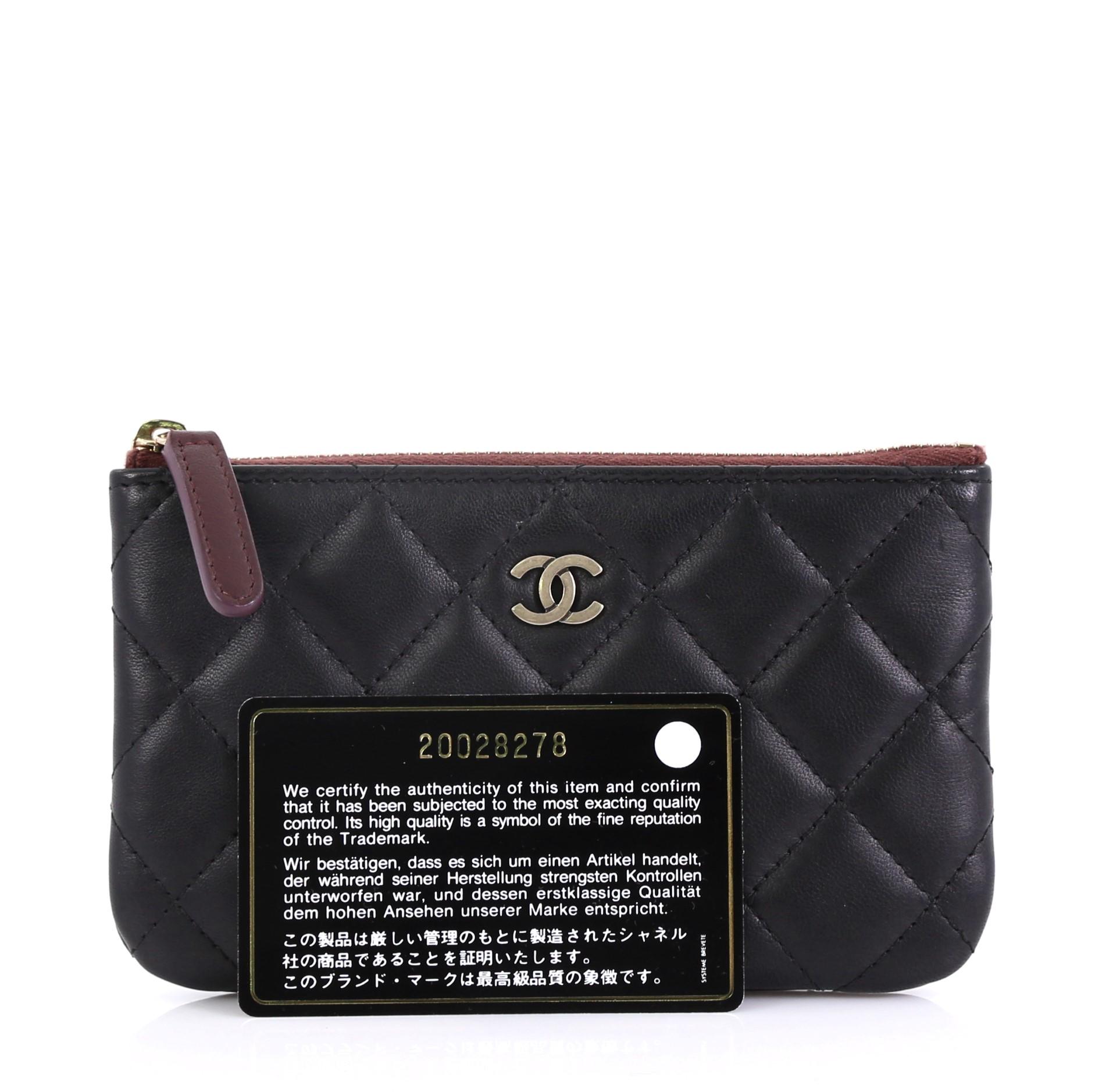 This Chanel Classic O Case Pouch Quilted Lambskin Mini, crafted from black quilted lambskin leather, features CC logo at front and gold-tone hardware. Its zip closure opens to a burgundy quilted nylon interior. Hologram sticker reads: 20028278.
