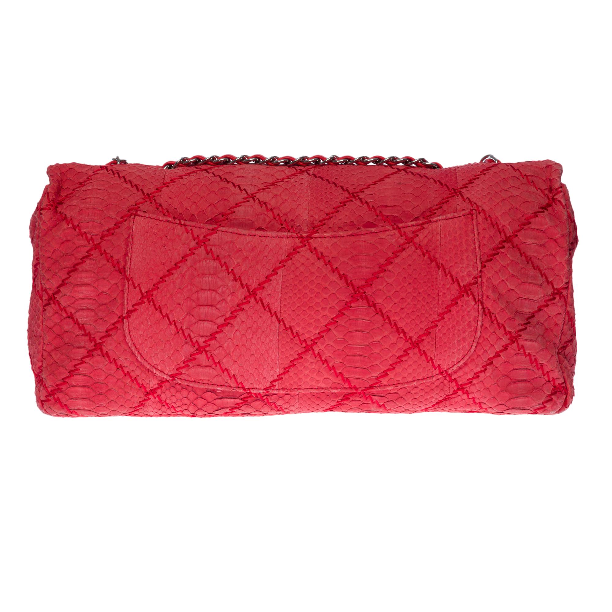 Klassische XL-Handtasche aus rotem Python, silberne Metallbeschläge, ein silberner Metallkettengriff, der mit rotem Leder verflochten ist und einen Hand- oder Schulterriemen ermöglicht.

Silberner CC-Metallverschluss auf der Klappe.
Eine aufgesetzte