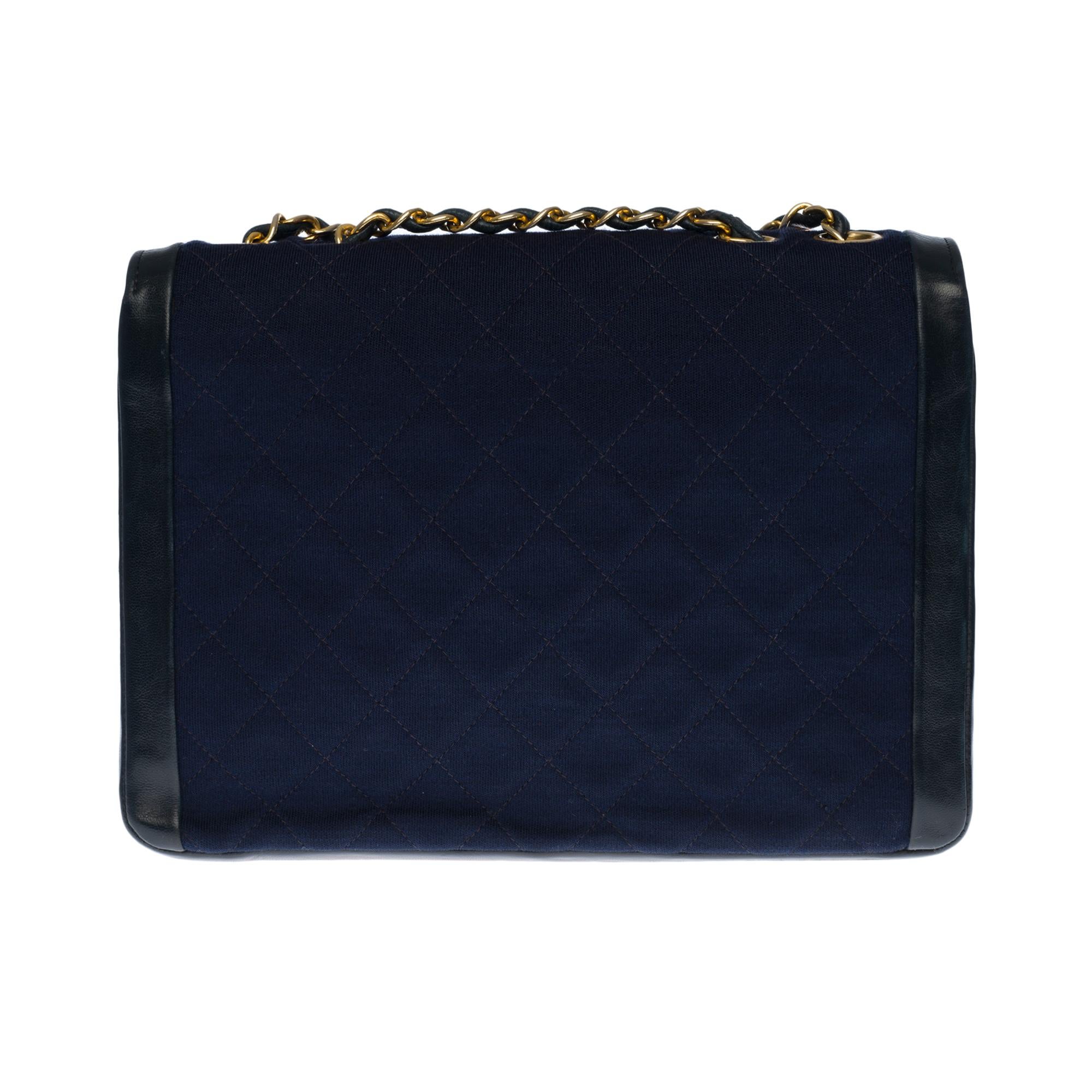 Lovely Chanel Classique two-material bag in navy blue quilted jersey and leather, gold-tone metal hardware, gold-tone metal handle intertwined with navy leather allowing a hand or shoulder support
Navy jersey quilted flap closure, gold metal CC