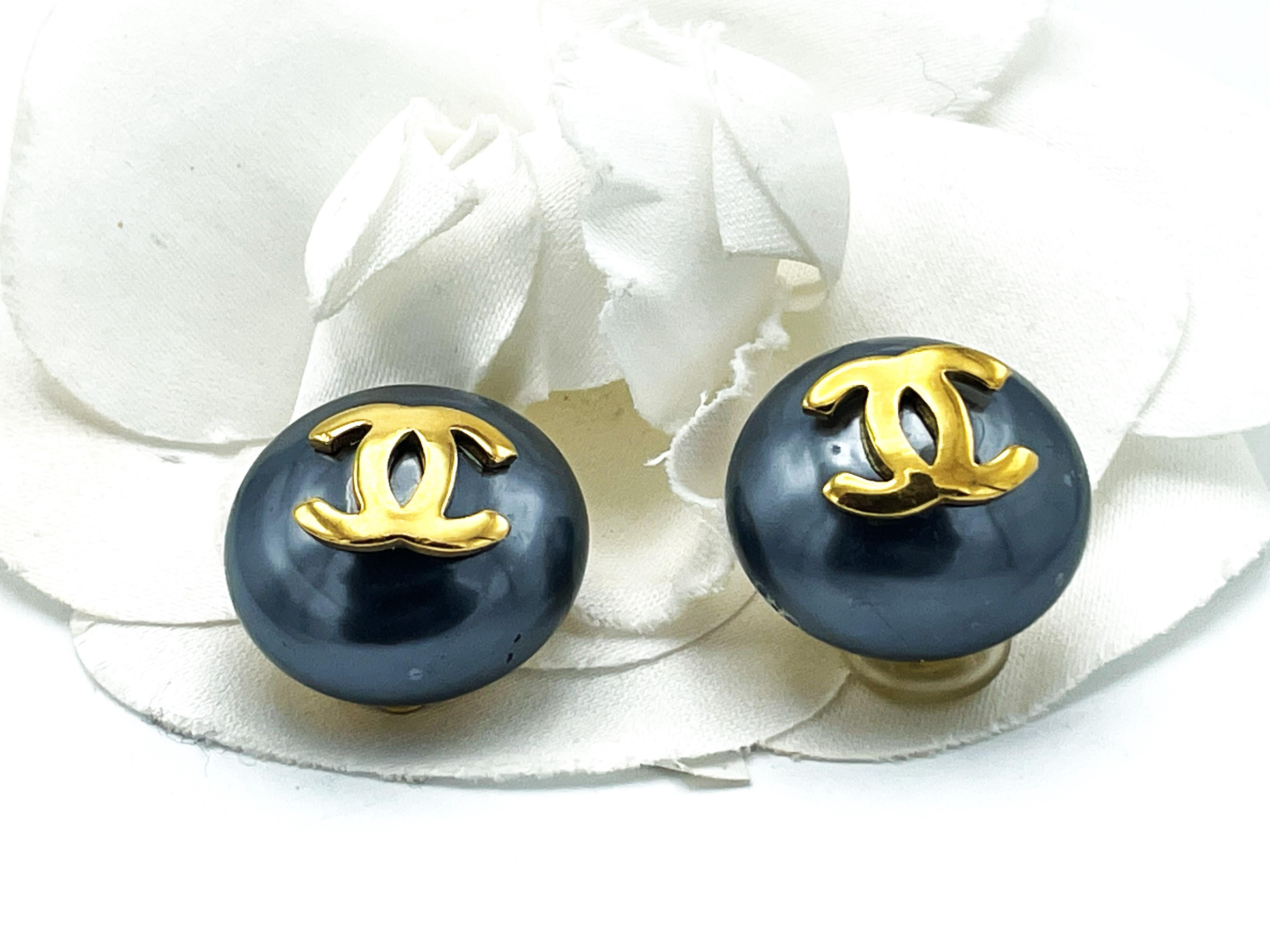 Fermaglio per orecchie Chanel vintage (Made in France), falso grande color antracite, perlina semicircolare decorata con logo CC dorato. Firmato Chanel 1970/80, in ottime condizioni. 

Dimensioni: Diametro 2,5 cm, profondità 1,6 cm , Logo CC L 1,6
