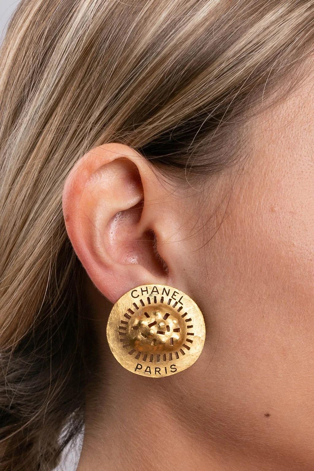 Chanel- (Made in France) Orecchini a clip in metallo dorato con incise le parole 