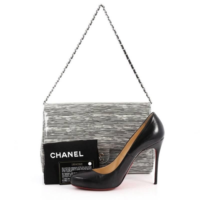 This authentic Chanel Clutch with Chain Printed Patent exudes an easy and chic style made for the modern woman. Crafted from black and white patent leather, this elegant flap clutch features woven-in leather silver chain strap and silver-tone