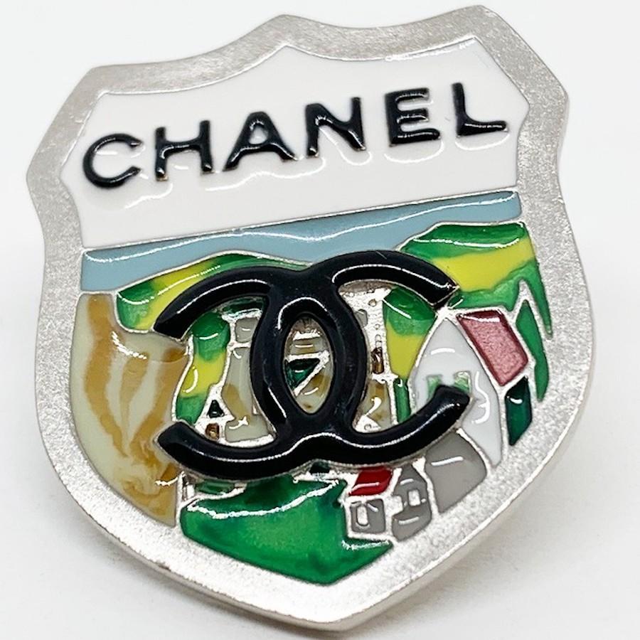 This Chanel Coat of arms pin is an attractive little accessory. 
Above is affixed the famous double C, as well as the name CHANEL. This pin will decorate your sweaters, lapels of  jackets, handbags, t-shirts. 
You can wear it alone or in