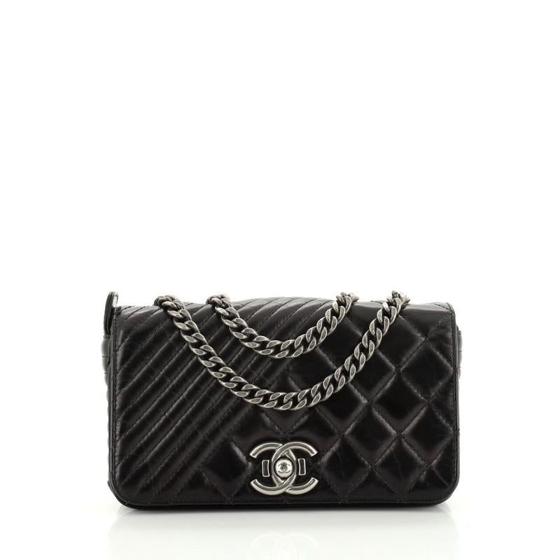 This Chanel Coco Boy Flap Bag Quilted Aged Calfskin Small, crafted from black quilted aged calfskin leather, features chain link strap and aged silver-tone hardware. Its CC boy push-lock closure opens to a red fabric interior with zip pocket.