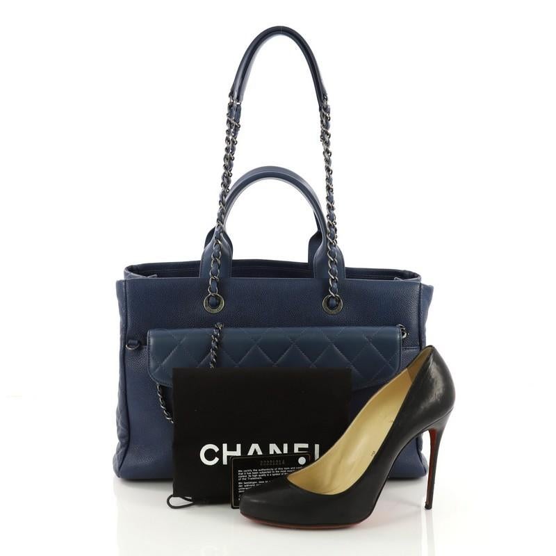 This Chanel Coco Break Shopping Tote Caviar Large, crafted from blue caviar leather, features dual rolled leather handles, woven in leather chain straps, front flap pocket, and aged silver-tone hardware. It opens to a burgundy leather interior