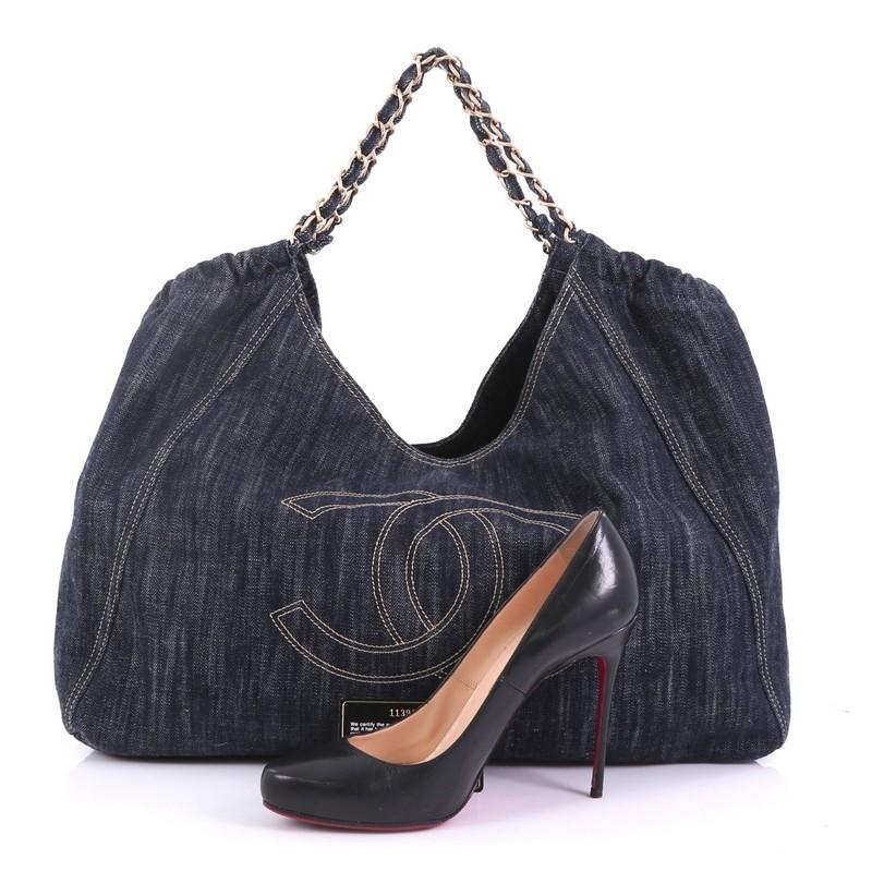 This Chanel Coco Cabas Denim Large, crafted in blue denim, features an oversized stitched CC frontal logo, ruched detailing, woven-in denim chain straps, and matte gold-tone hardware. Its magnetic snap closure opens to a beige fabric interior with