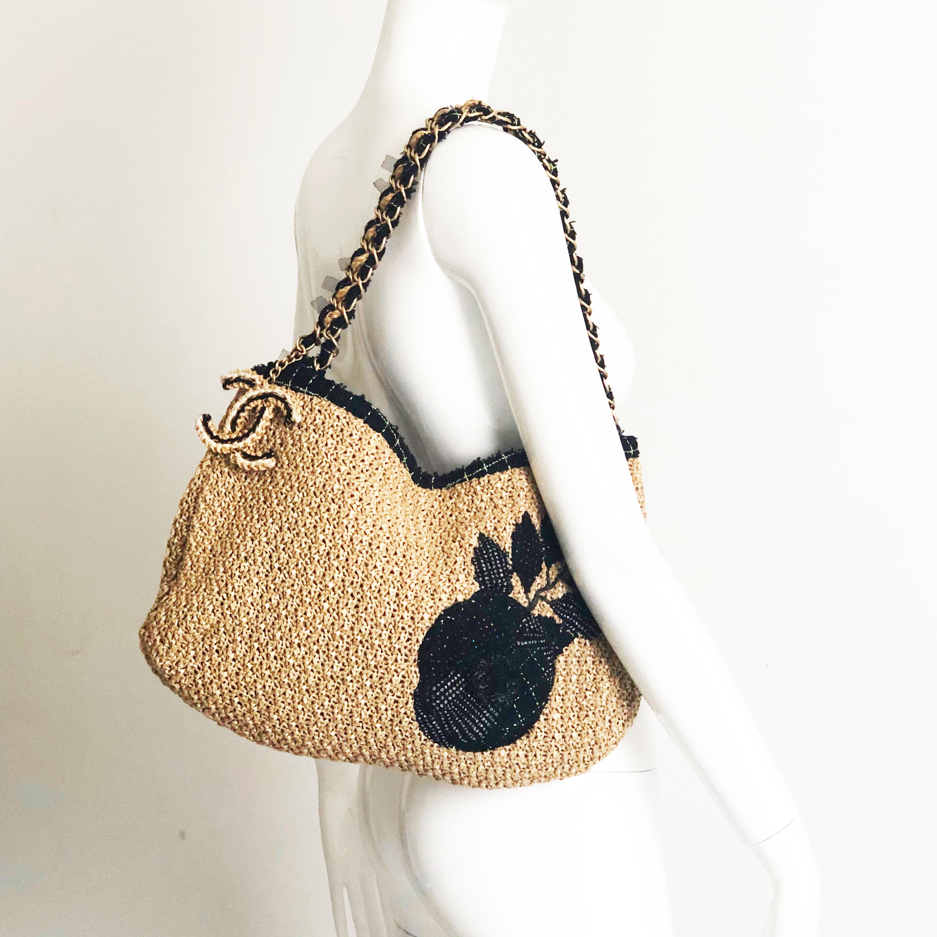 Authentic, preowned Chanel Coco Country Camellia Woven Straw shoulder bag, circa 2010. Woven straw trimmed in boucle wool w/gold metal hardware & attached CC logo charm. Lined in fabric w/1 zip pocket, 1 open split pocket. Fastens w/magnetic