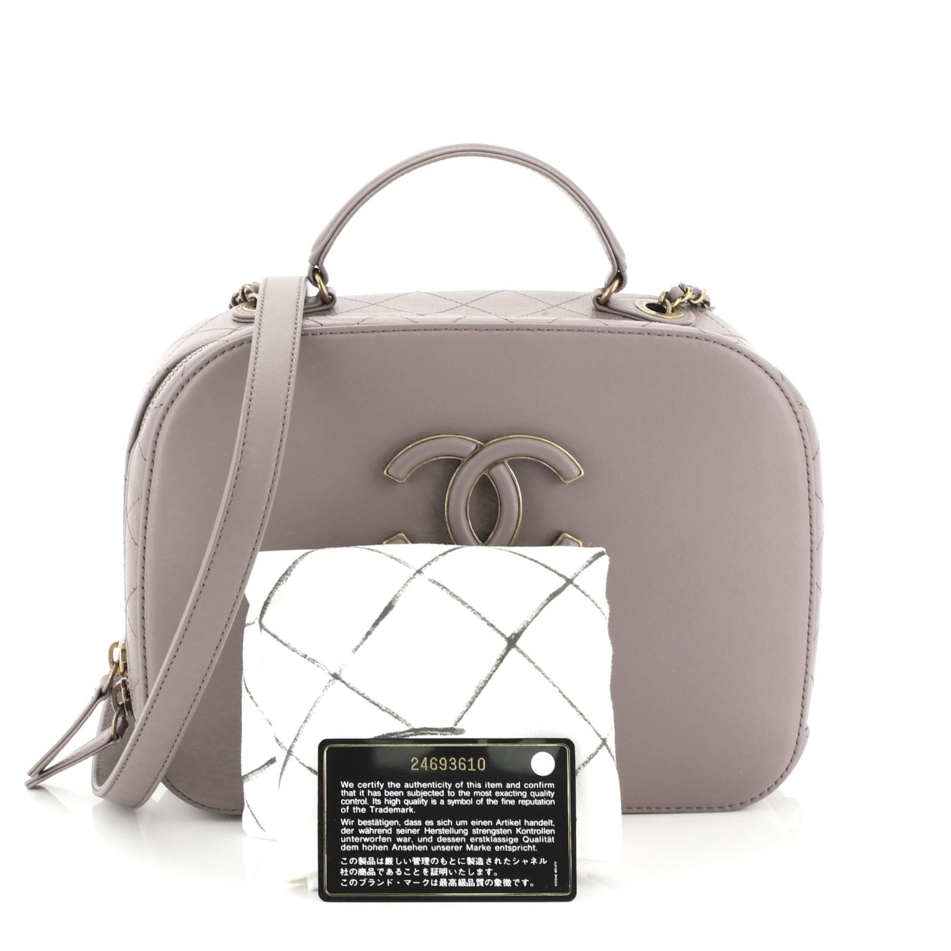 This Chanel Coco Curve Vanity Case Calfskin and Quilted Goatskin Medium, crafted in purple calfskin and quilted goatskin, features a leather top handle, woven-in leather chain strap with leather pad, CC logo at front, exterior back zip pocket, and