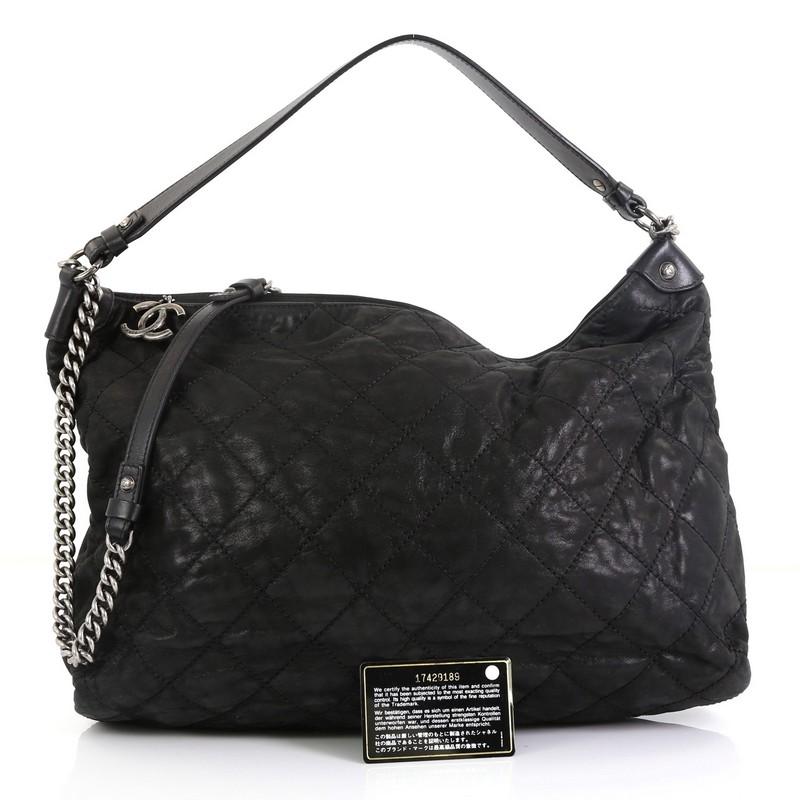 This Chanel Coco Daily Hobo Quilted Iridescent Calfskin Large, crafted in black quilted iridescent calfskin leather, features flat leather handle, chain link strap with leather pad, and aged silver-tone hardware. Its zip closure opens to a gray