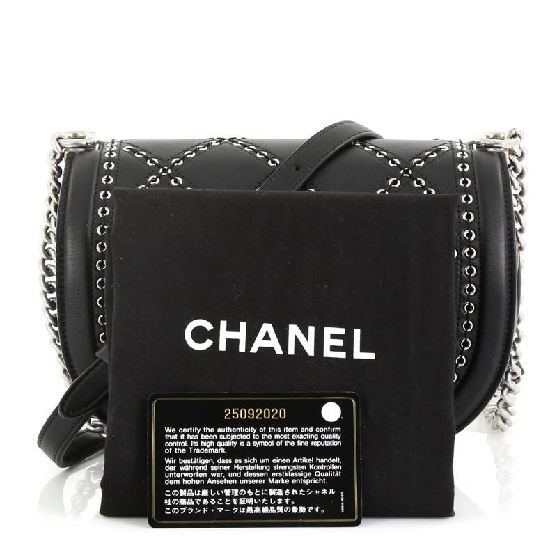 This Chanel Coco Eyelets Round Flap Bag Quilted Calfskin Small, crafted in black quilted calfskin leather, features chain link strap with leather pad and silver-tone hardware. Its CC turn-lock closure opens to a black fabric interior with zip