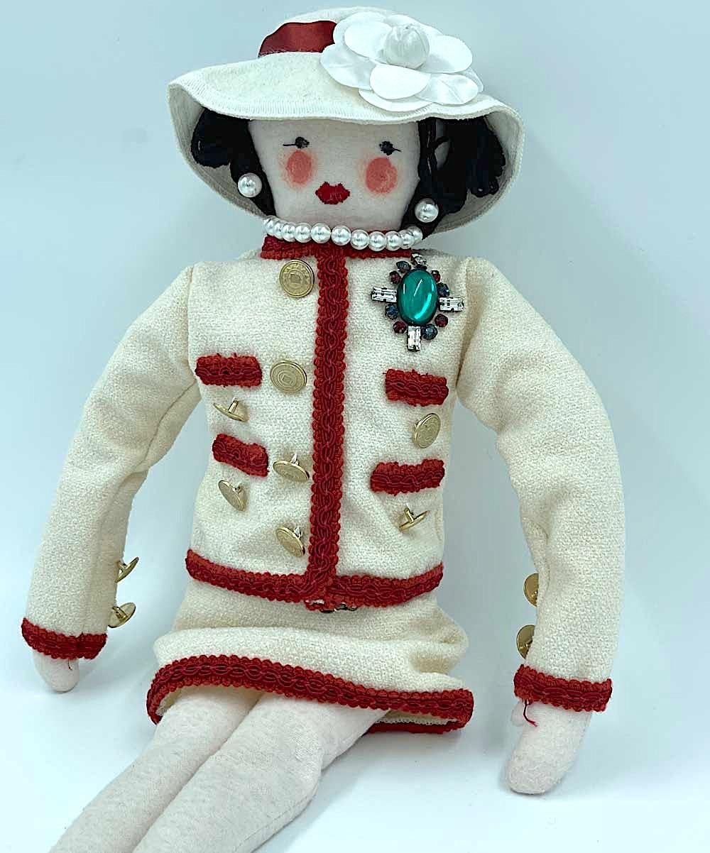 Extremely rare. Authentic. Iconic collector's item. 
The doll is dressed in a classic Chanel suit with CC buttons. She has a beautiful brooch, a pearl necklace, pearly earrings. 
This Coco doll was created in 2010 for the reopening of the Chanel