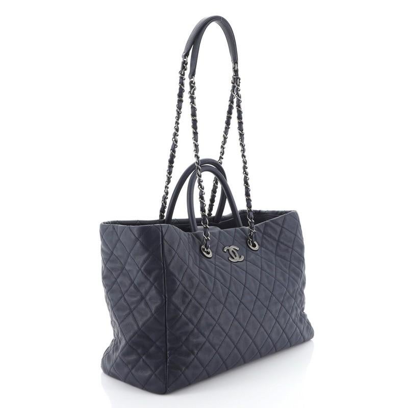 This Chanel Coco Handle Shopping Tote Quilted Caviar, crafted in blue quilted caviar leather, features dual rolled leather handles, woven-in leather chain link straps with leather pads, exterior back slip pocket, and aged silver-tone hardware. Its