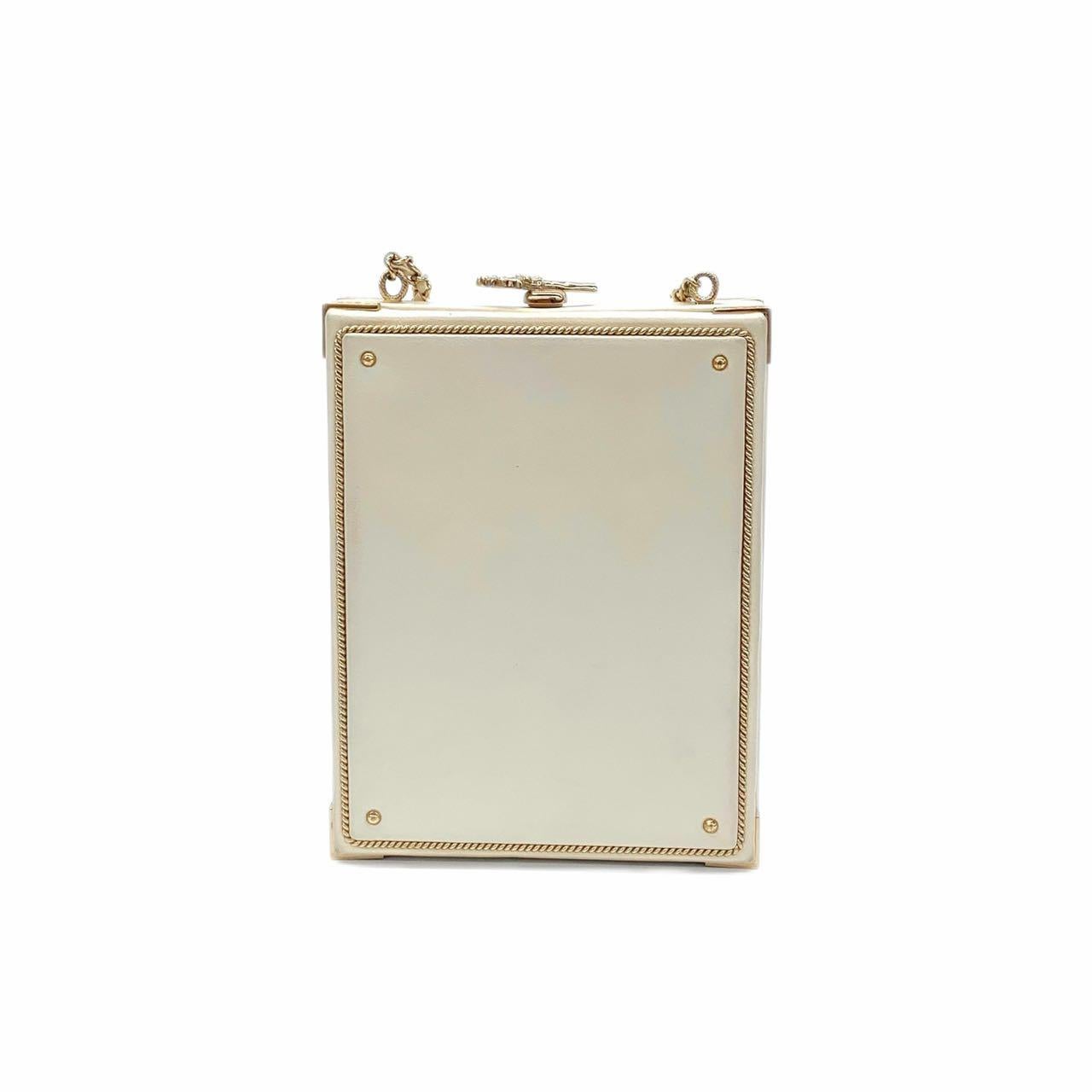 Whiting, l'authentique Chanel Coco in Ritz Key Card Minaudière dans un mélange captivant de blanc et d'or. Ce mini sac à bandoulière chic met en valeur l'opulence du cuir d'agneau dans un blanc immaculé, élégamment complété par des coins métalliques