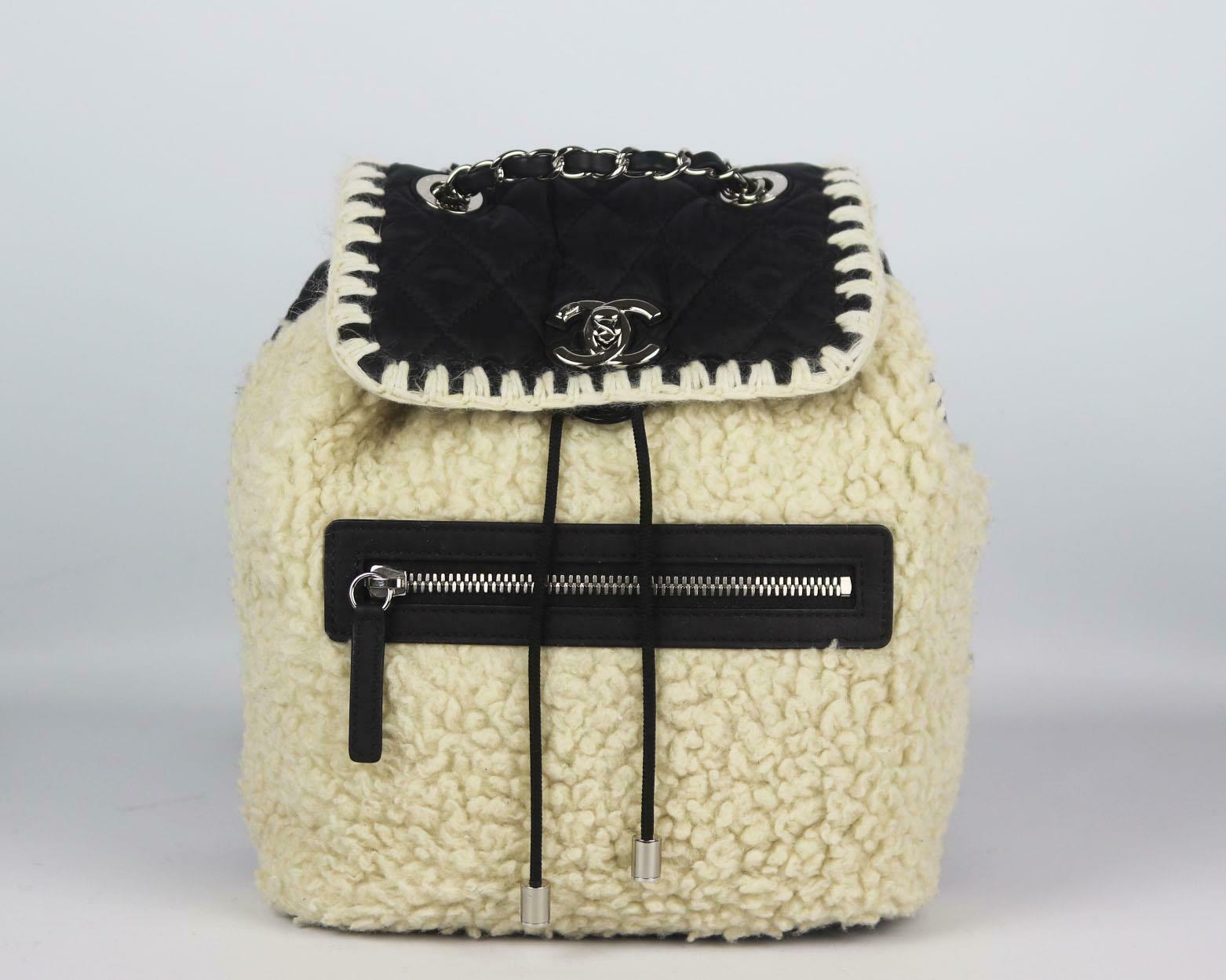 Made in Italy, this beautiful Chanel 'Coco Neige' backpack has been made from cream shearling trimmed and black nylon exterior with black nylon interior, this piece is decorated with Chanel's silver twist-lock logo on the front and finished with