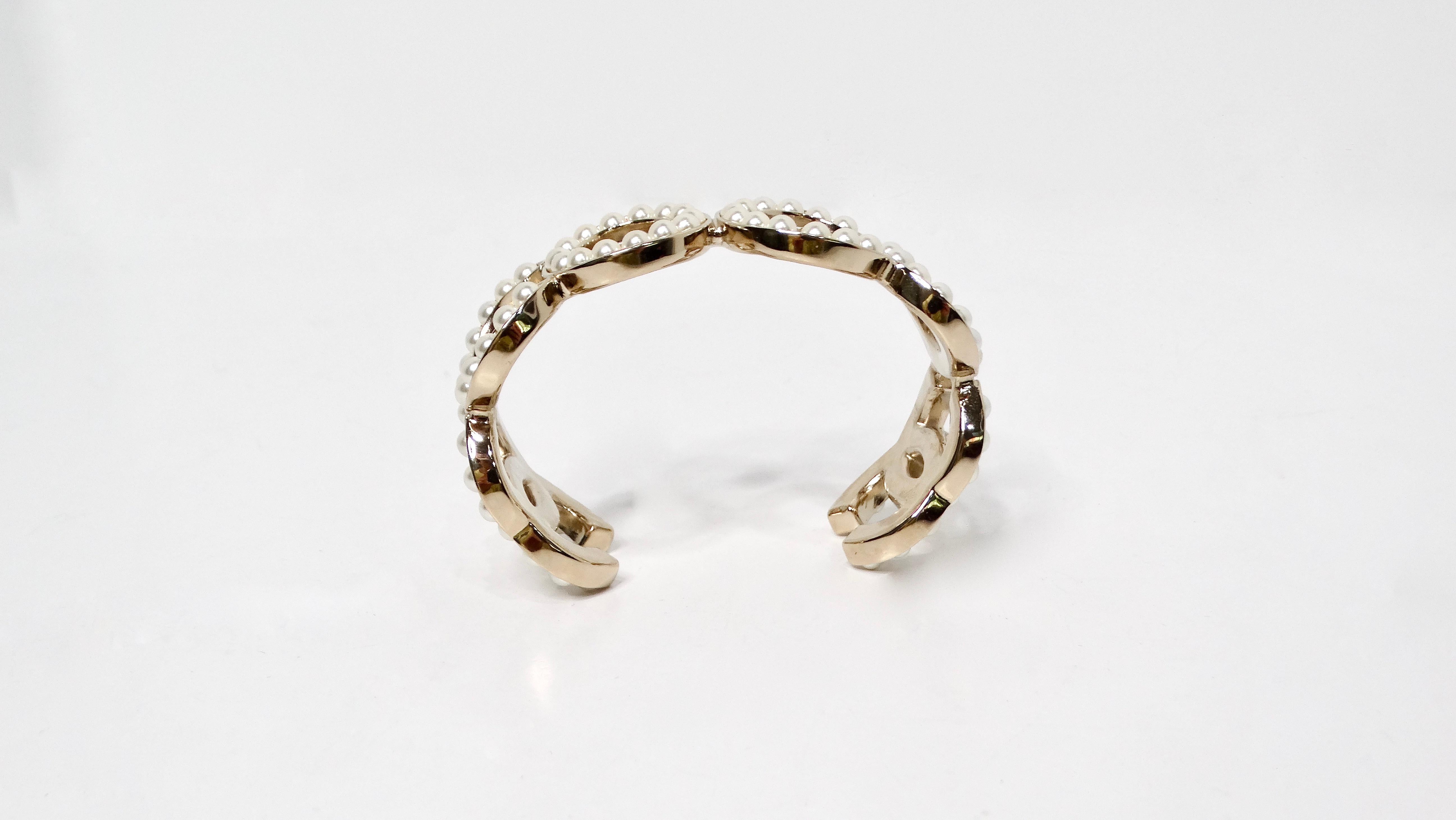 La manchette Chanel COCO Pearl 14K Gold Plated est une pièce exquise qui incarne sans effort l'essence du luxe et de la sophistication. Cette magnifique manchette est ornée de perles fantaisie glamour artistiquement disposées pour épeler 