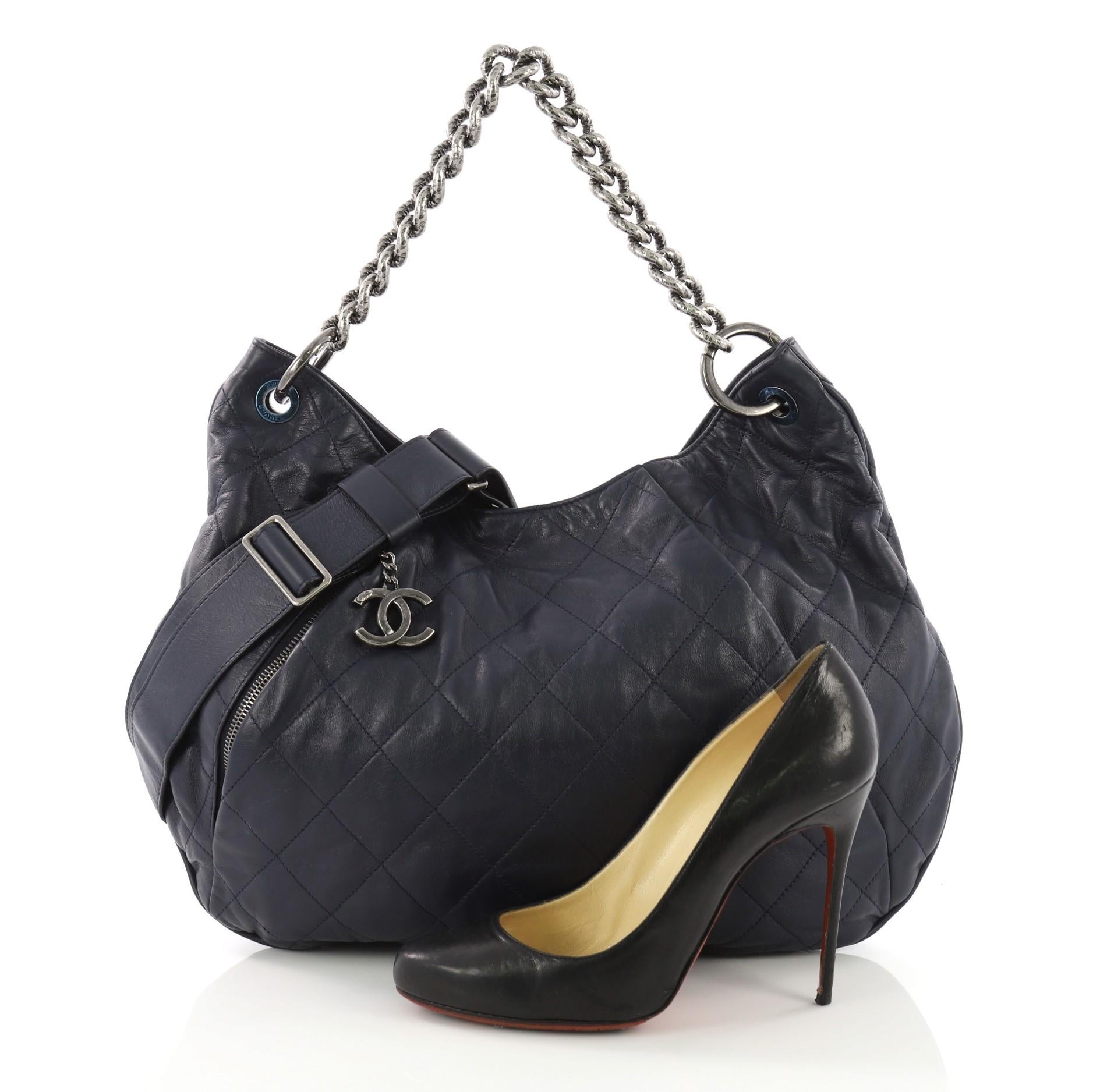 This Chanel Coco Pleats Hobo Quilted Calfskin Large, crafted in navy quilted calfskin leather, features stylized chain strap, exterior zip pocket, and aged silver-tone hardware. Its zip closure opens to a blue fabric interior with side zip pocket.