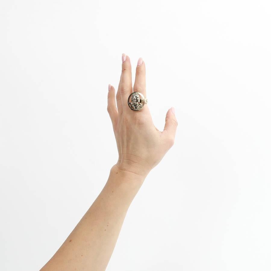 Never worn, exquisite Chanel ring, withe the famous Gabrielle Chanel, coco, figure and the iconic CC symbol. In pale gold tone metal, the ring is a size 50 French, or 5 US. Diameter of the ring is 1,59 cm and diameter of the circle with the figure