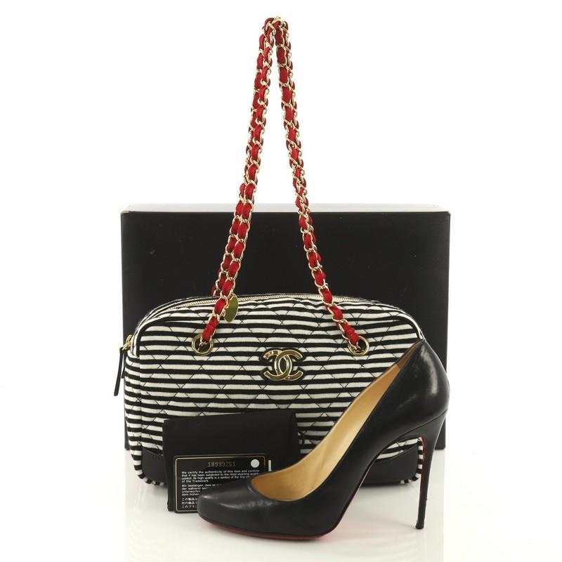 This Chanel Coco Sailor Camera Bag Quilted Jersey and Lambskin Medium, crafted in black and white quilted jersey with black lambskin leather, features woven in leather chain link strap and gold-tone hardware. Its zip closure opens to a red fabric