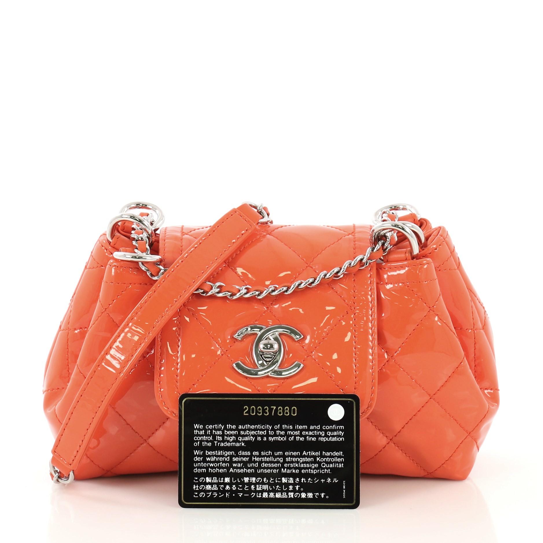 This Chanel Coco Shine Accordion Flap Bag Quilted Patent Mini, crafted from orange quilted patent leather, features woven-in leather chain strap with leather pad, frontal flap, and silver-tone hardware. Its CC turn-lock closure opens to a black