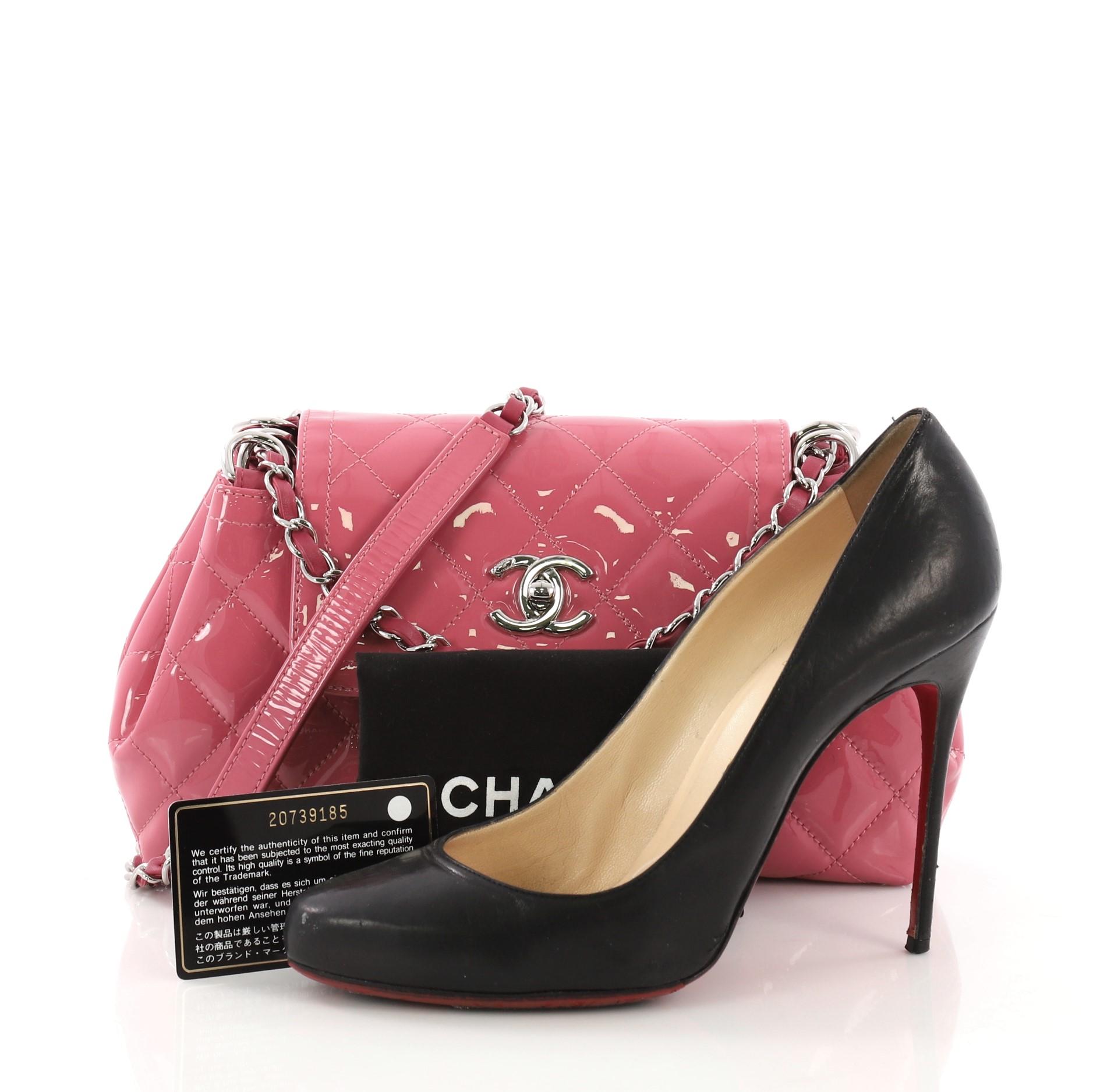 This Chanel Coco Shine Accordion Flap Bag Quilted Patent Small, crafted from pink quilted patent leather, features chain link leather strap threaded through eyelets, frontal flap with signature CC turn-lock closure, and silver-tone hardware. Its