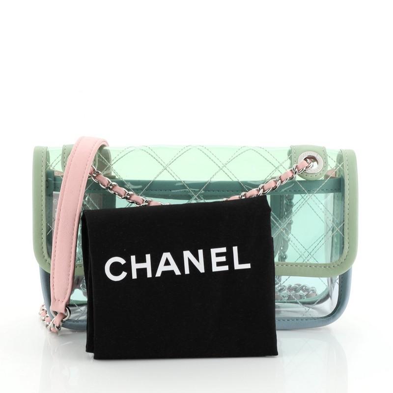This Chanel Coco Splash Flap Bag Quilted PVC With Lambskin Medium, crafted from clear quilted PVC with lambskin leather, features woven-in leather chain strap with leather pad, leather trim, exterior back slip pocket, and silver-tone hardware. Its