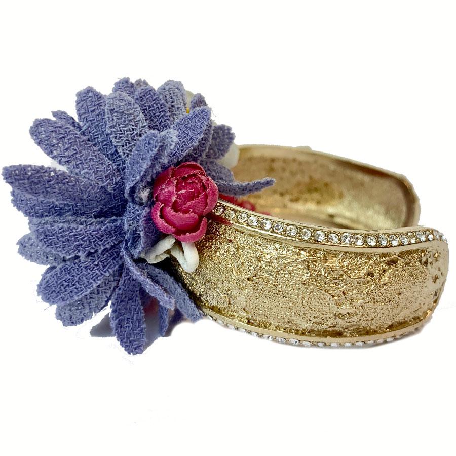 Superb rigid gold-colored metal bracelet set with purple and pink fabric flowers and yellow and pink plastic inserts.
The CHANEL flower bracelet is set with small white rhinestones and a rhinestone CC on the side. Rare jewel and collector.
Jewel in