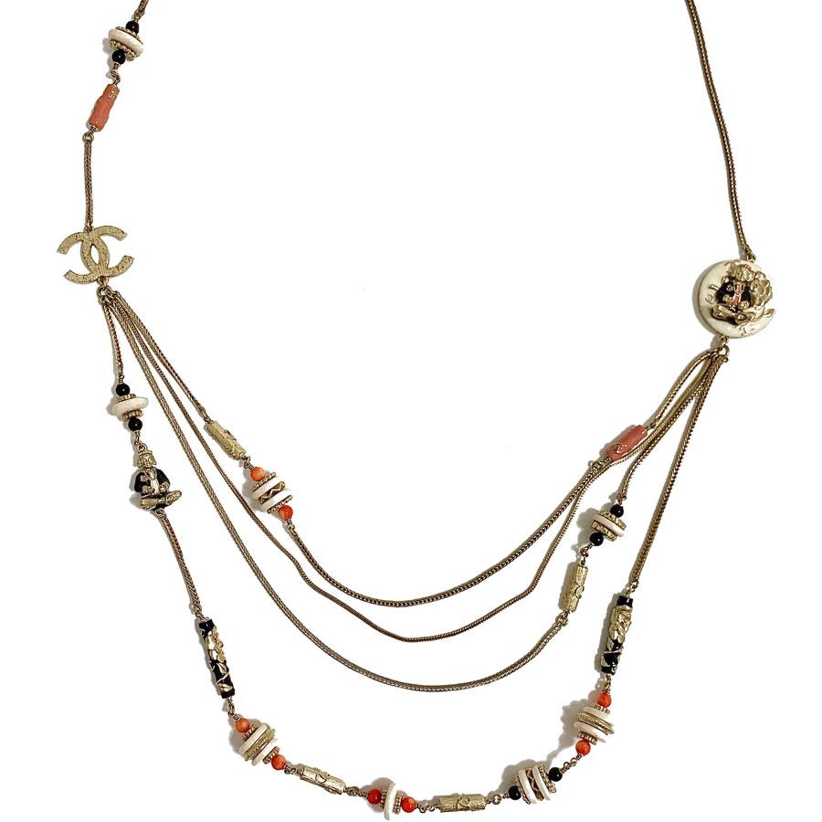 CHANEL collector's necklace from the Métiers d'Art Paris Shanghai Collection. The long necklace is composed of a girl chain in palm knit, charms made of resins, metal or a mixture of the two, a golden CC, camellias, a figurine sitting cross-legged