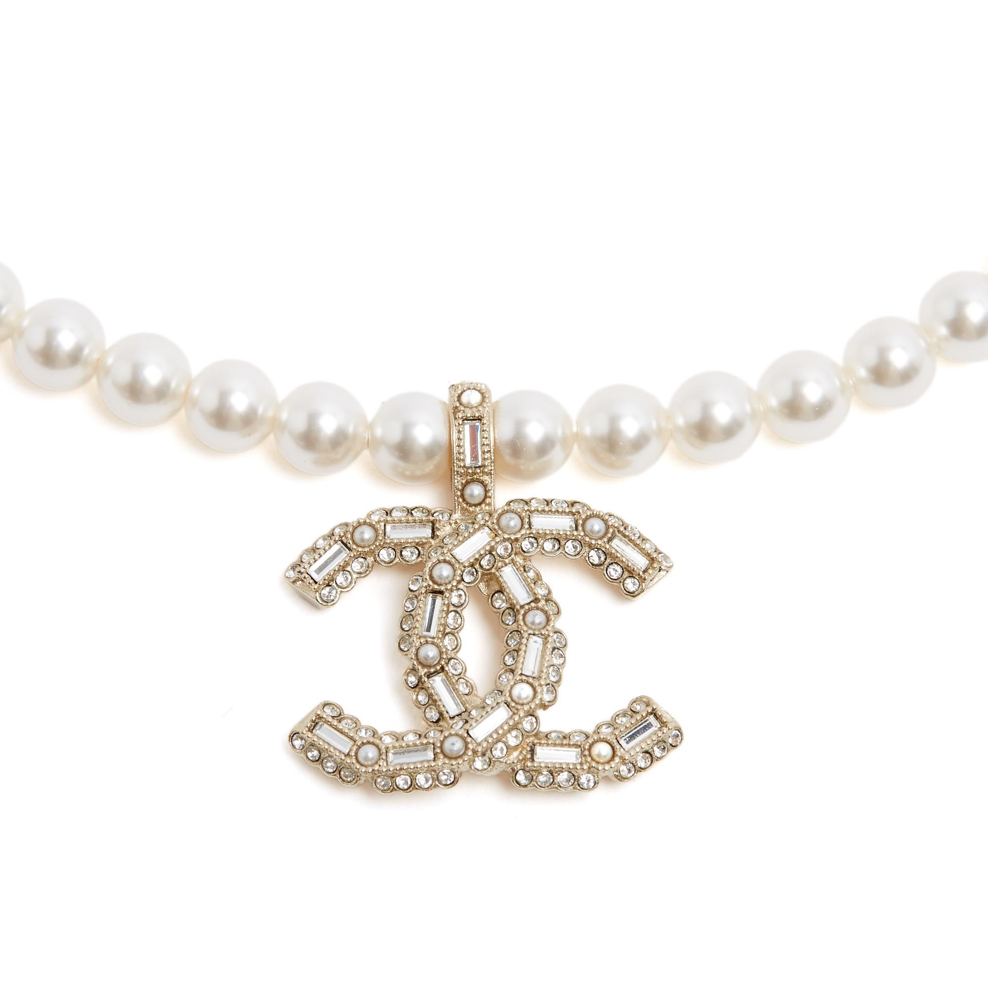 Chanel 2022 collection choker necklace, bestehend aus einer Reihe weißer, perlmuttartiger Perlen, die durch einen Karabinerverschluss und eine Kette mit Mini-CC-Logo verlängert werden, und einem großen CC-Logo aus goldenem Metall, das mit