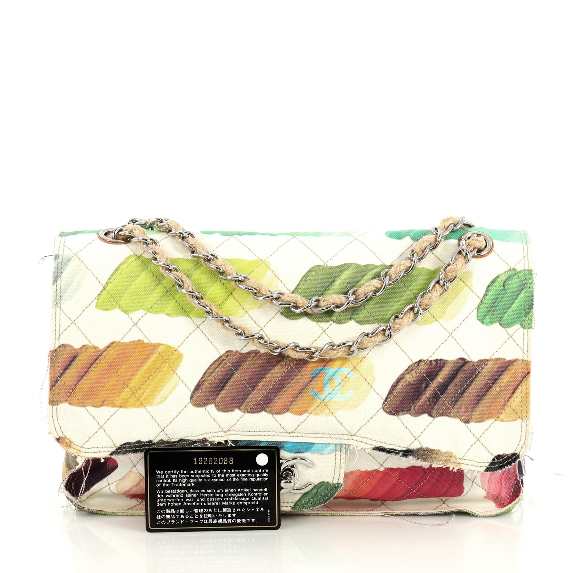 This Chanel Colorama Flap Bag Quilted Watercolor Canvas Jumbo, crafted in white quilted canvas, features woven-in jute chain link strap, multicolor abstract brush strokes, exterior back pocket, and silver-tone hardware. Its CC turn lock closure