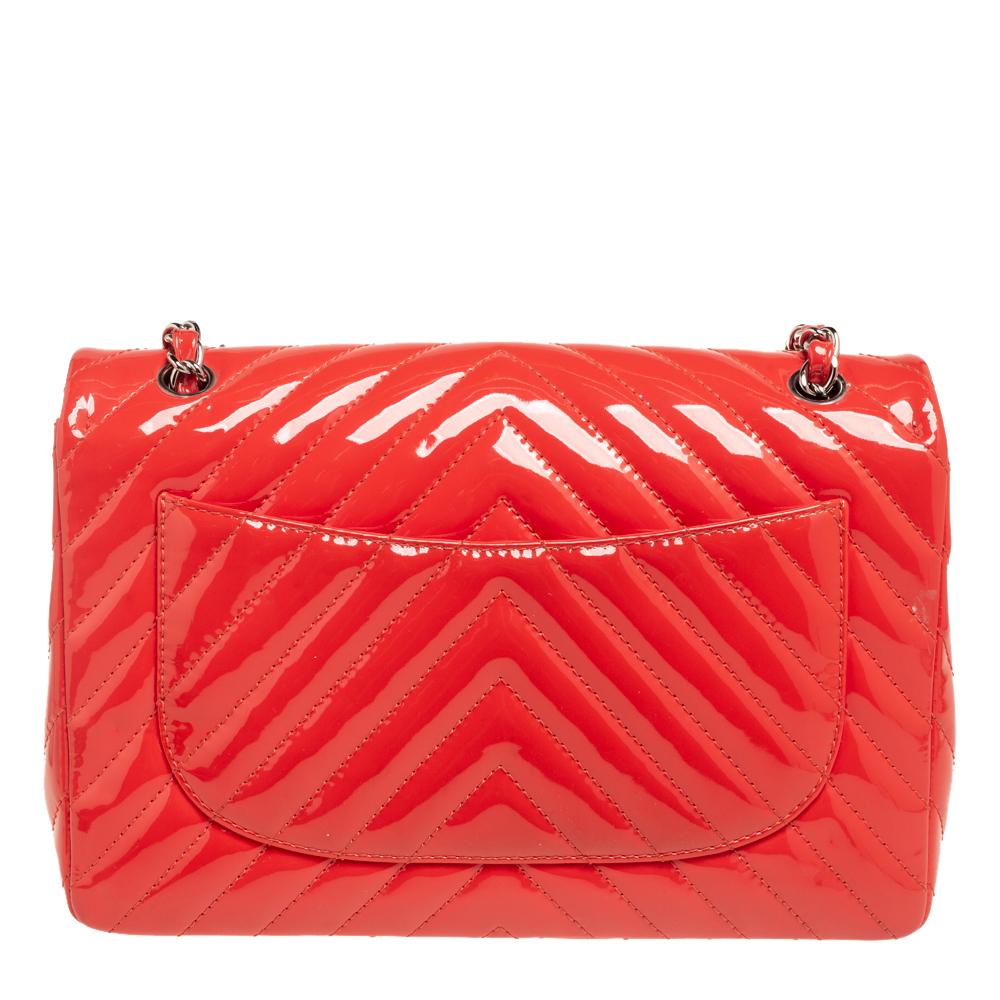 Crafted from glossy patent leather, this Chanel bag is a classic beauty. Its coral exterior is designed with chevron quilting and is accented with silver-tone hardware. It features a CC logo lock and chain-leather handles that can be converted into