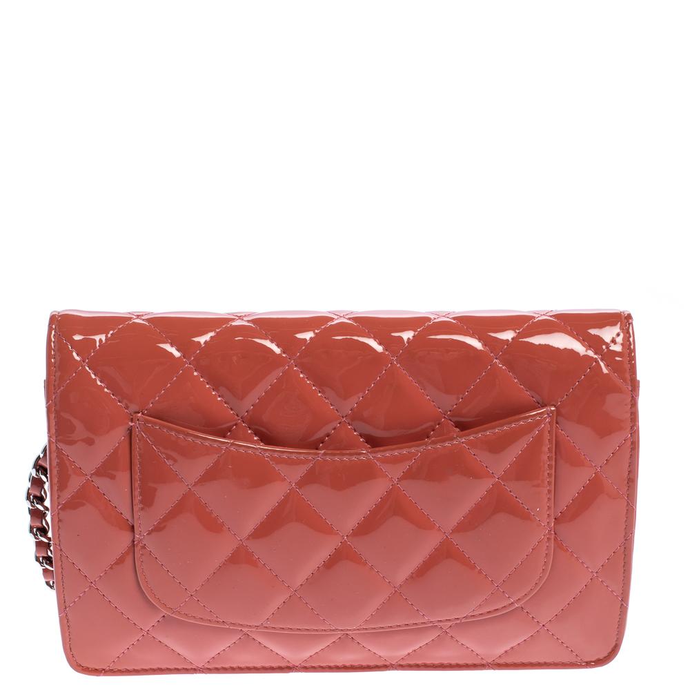 Constructed from coral orange patent leather, this wallet on chain from Chanel is quite impressive! It features an exterior that is detailed with the signature quilted pattern and the iconic CC logo in silver-tone. It opens to a leather and fabric