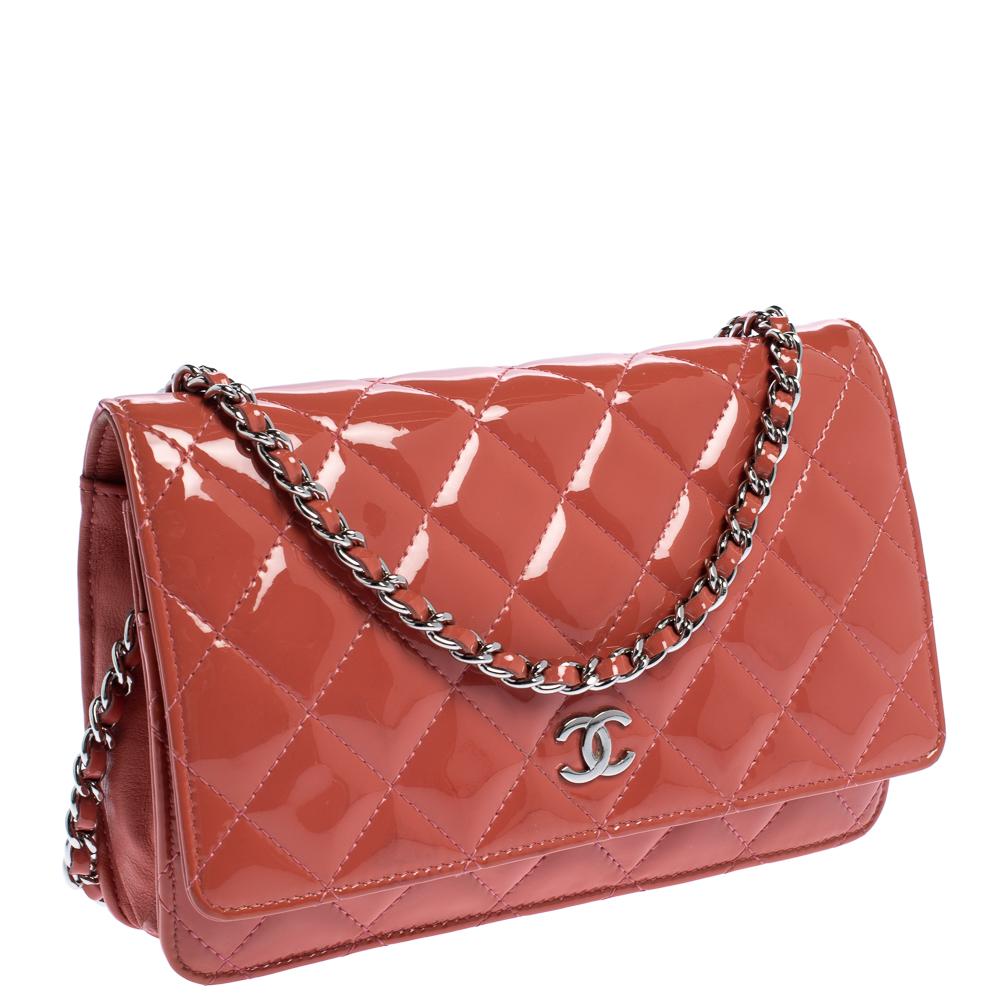 Constructed from coral orange patent leather, this wallet on chain from Chanel is quite impressive! It features an exterior that is detailed with the signature quilted pattern and the iconic CC logo in silver-tone. It opens to a leather and fabric