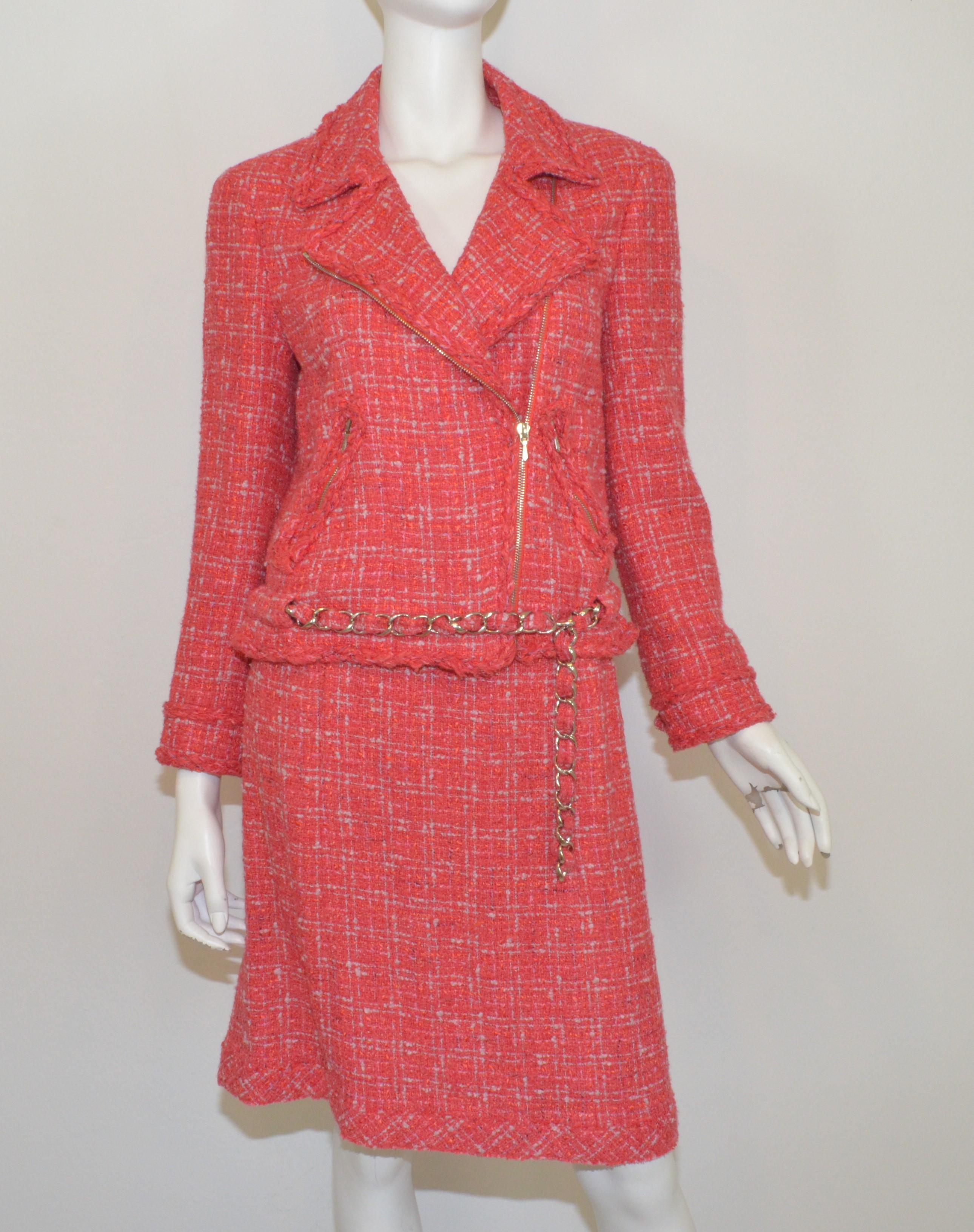 Chanel 2006 P collection Skirt Suit — Featured in a coral/red tweed with silver tone hardware throughout. Moto style jackets has a zipper fastening, zippered pockets, silver buttons at the cuffs of the sleeves, and an optional chain belt. Skirt has