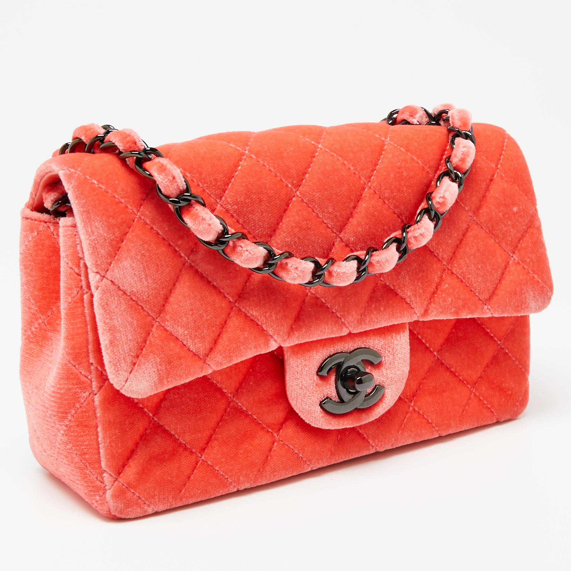 The Chanel New Mini Classic Flap bag is a sized-down version of the icon. We have here the one in coral velvet. It has the signature quilt, the CC lock, and the brand label inside the interior. The long woven chain allows shoulder as well as