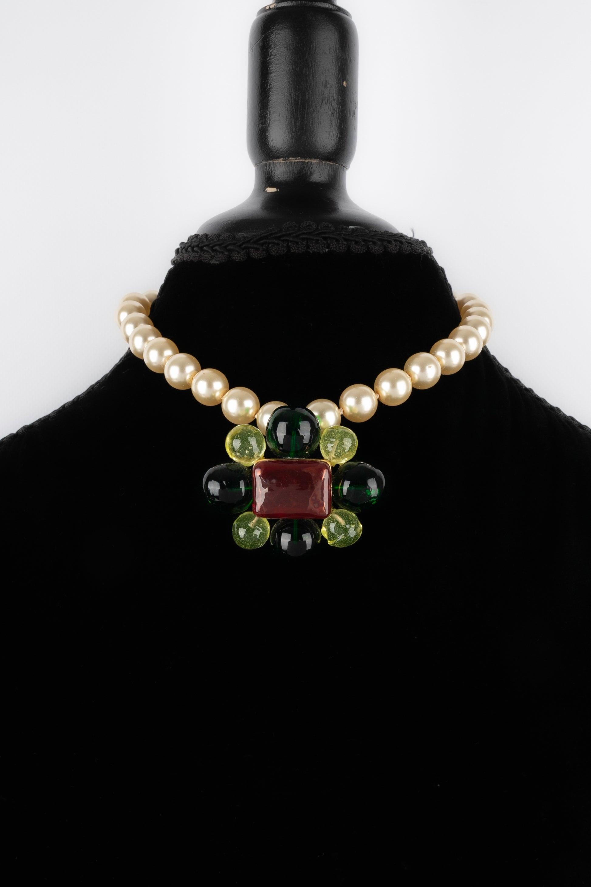 Chanel - (Made in France) Short costume pearl necklace holding a golden metal brooch pendant with glass paste. 1997 Fall-Winter Collection.

Additional information:
Condition: Very good condition
Dimensions: Length: 39 cm
Period: 20th