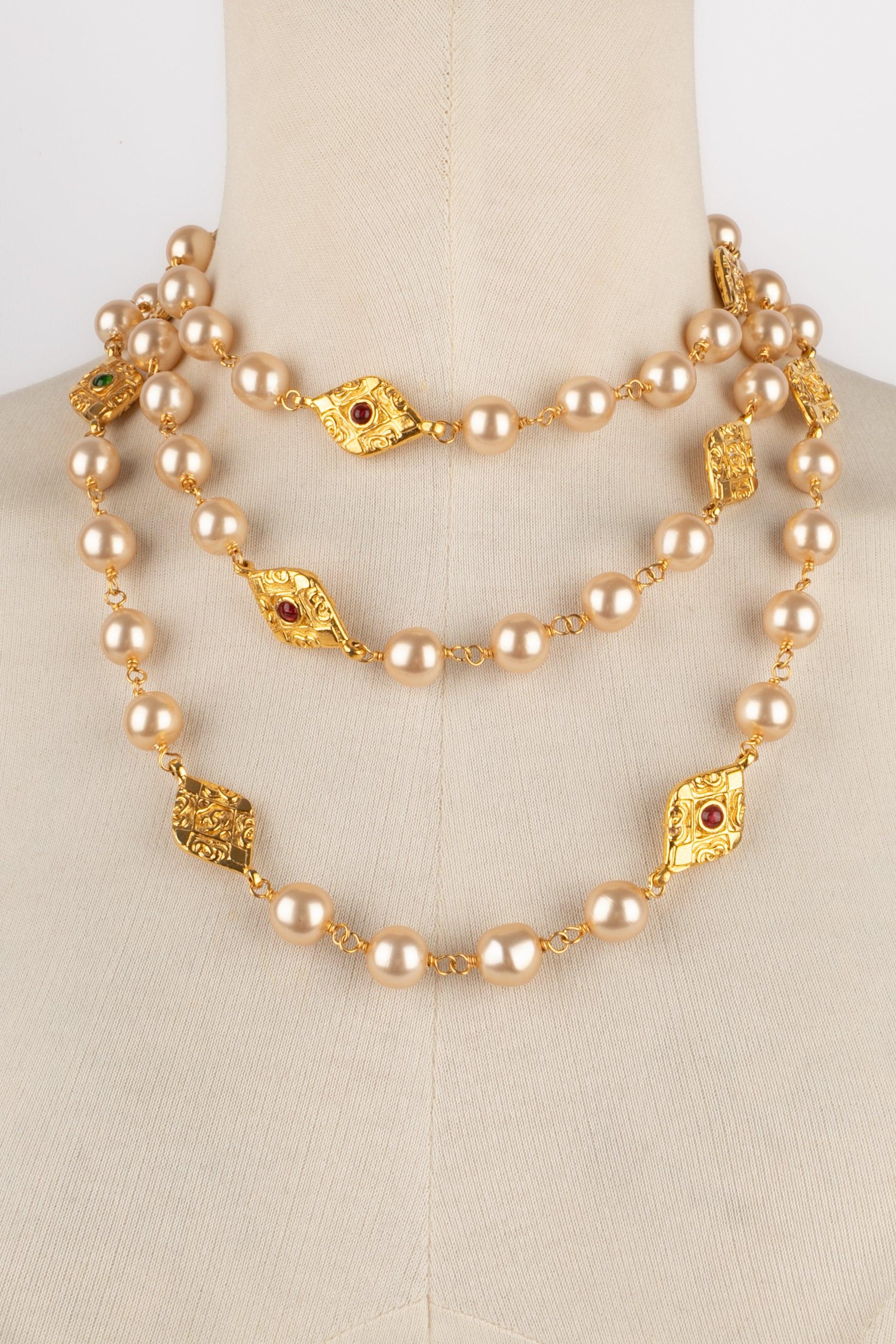 Chanel - (Made in France) Costume pearl sautoir necklace with golden metal medallions centered with tiny glass paste. Jewelry from the late 1980s.

Additional information:
Condition: Very good condition
Dimensions: Length: 150 cm
Period: 20th
