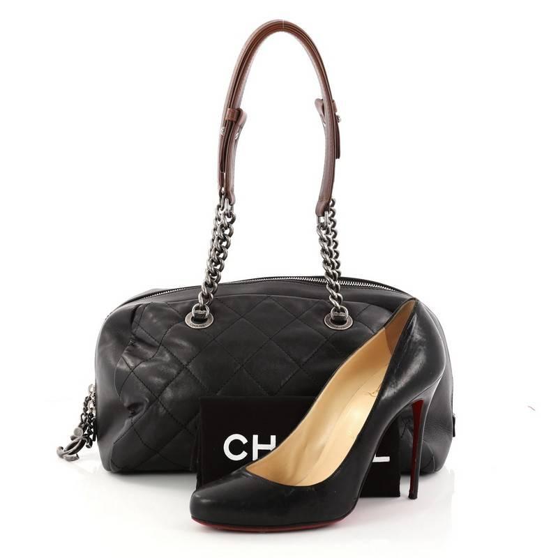 This authentic Chanel Country Chic Bowler Quilted Leather Medium is fun and functional, perfect for your everyday use. Crafted from black quilted leather, this gorgeous bag features dual chain-link straps with leather shoulder pads, Chanel CC logo