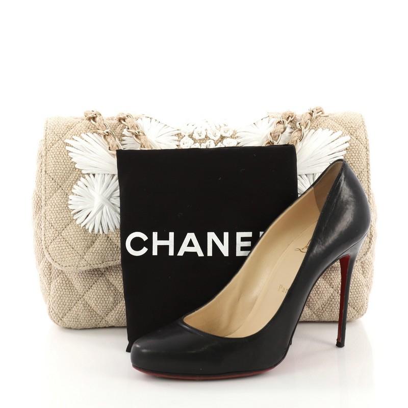 This Chanel Country Coco Flap Bag Floral Embroidered Quilted Raffia Jumbo, crafted in beige floral embroidered quilted raffia, features woven-in raffia chain strap, embroidered floral decoration and gold-tone hardware. Its turn-lock closure opens to