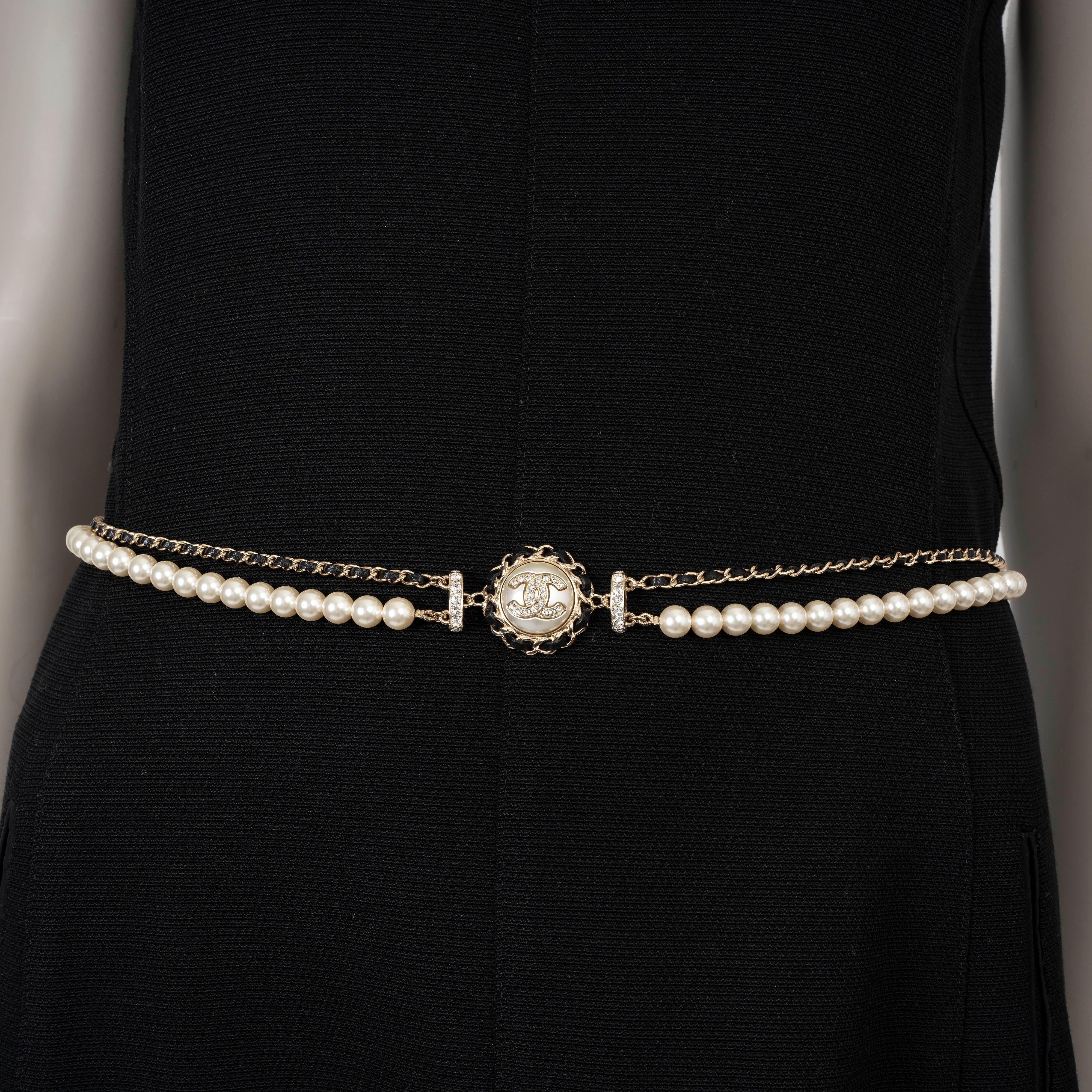 This 100% authentic Chanel chain belt exudes timeless elegance, crafted in gold-tone metal with an interwoven black leather strap and a faux pearl strand for a luxurious touch. The centerpiece features a crystal-embellished CC button, adding iconic