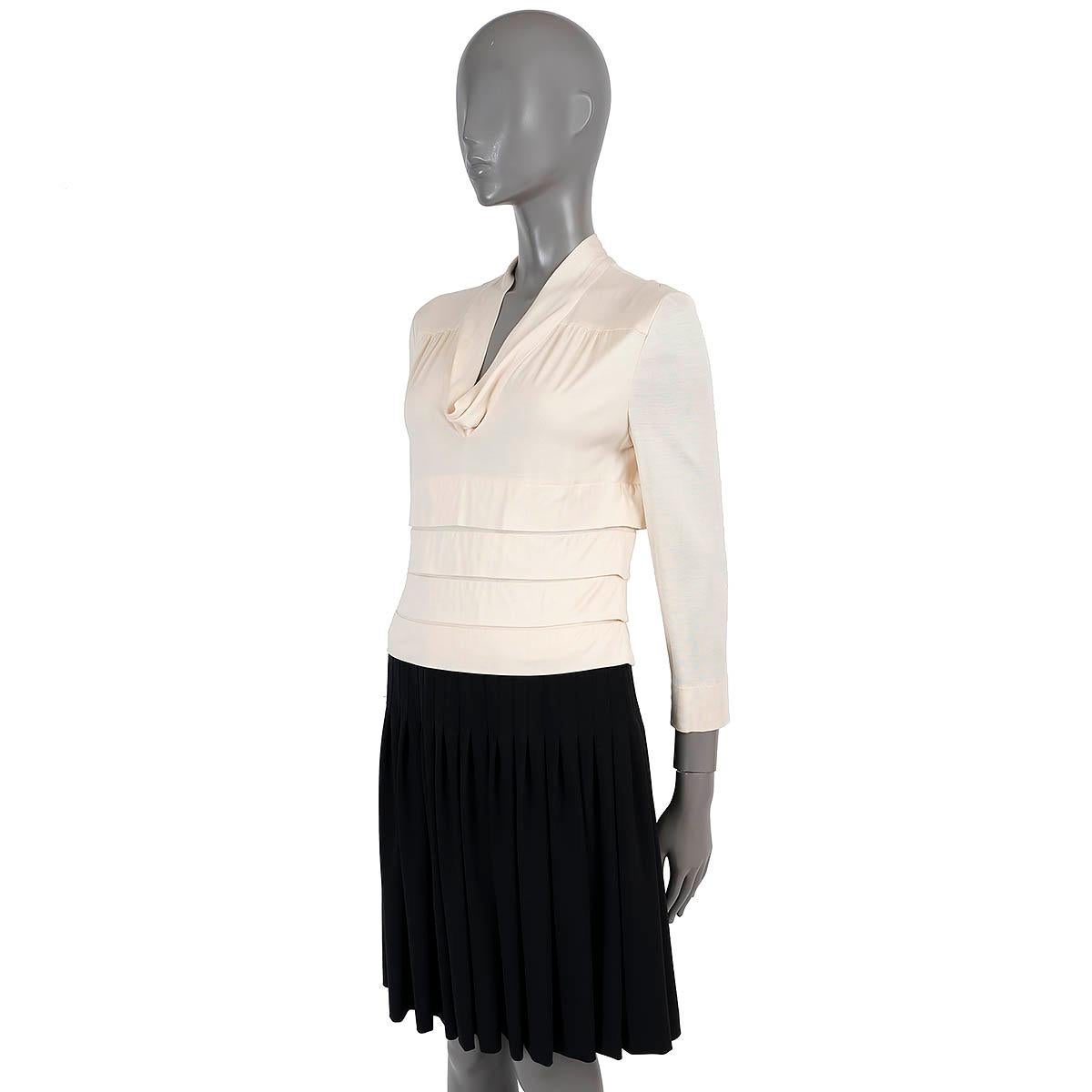 100% authentic Chanel colorblock dress. Features a cream top in jersey silk (100%) with cowl neck and pleated details and a black pleated skirt in wool (100%). Opens with a concealed zipper in the back and is lined in silk (100%). Has been worn and