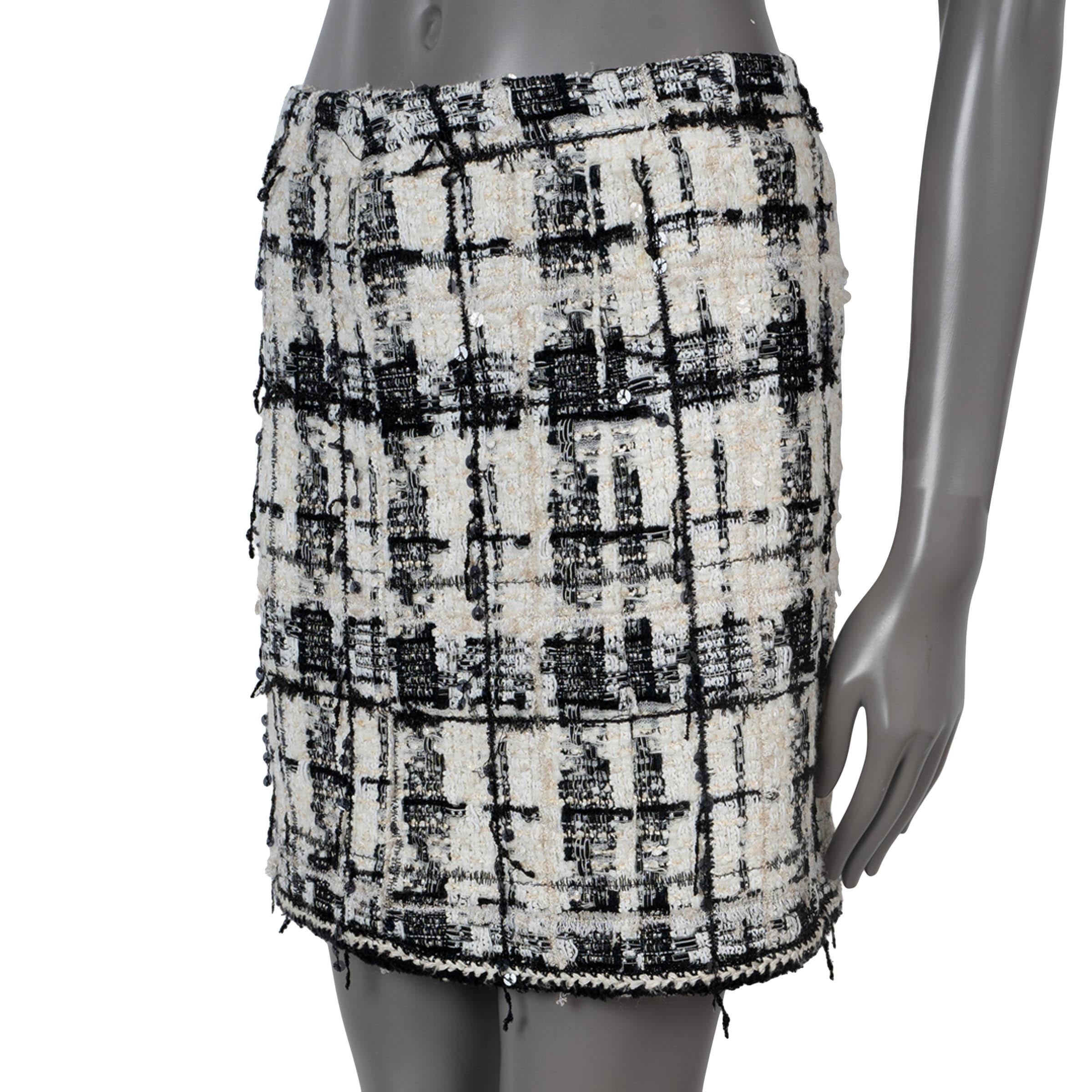 100% authentic Chanel mini skirt in cream and black plaid tweed nylon (30%), viscose (24%), metal (14%), cotton (9%), rayon (8%), polyester (8%) and wool (7%). Features sequins through-out and braided trim along the bottom hem. Opens with a