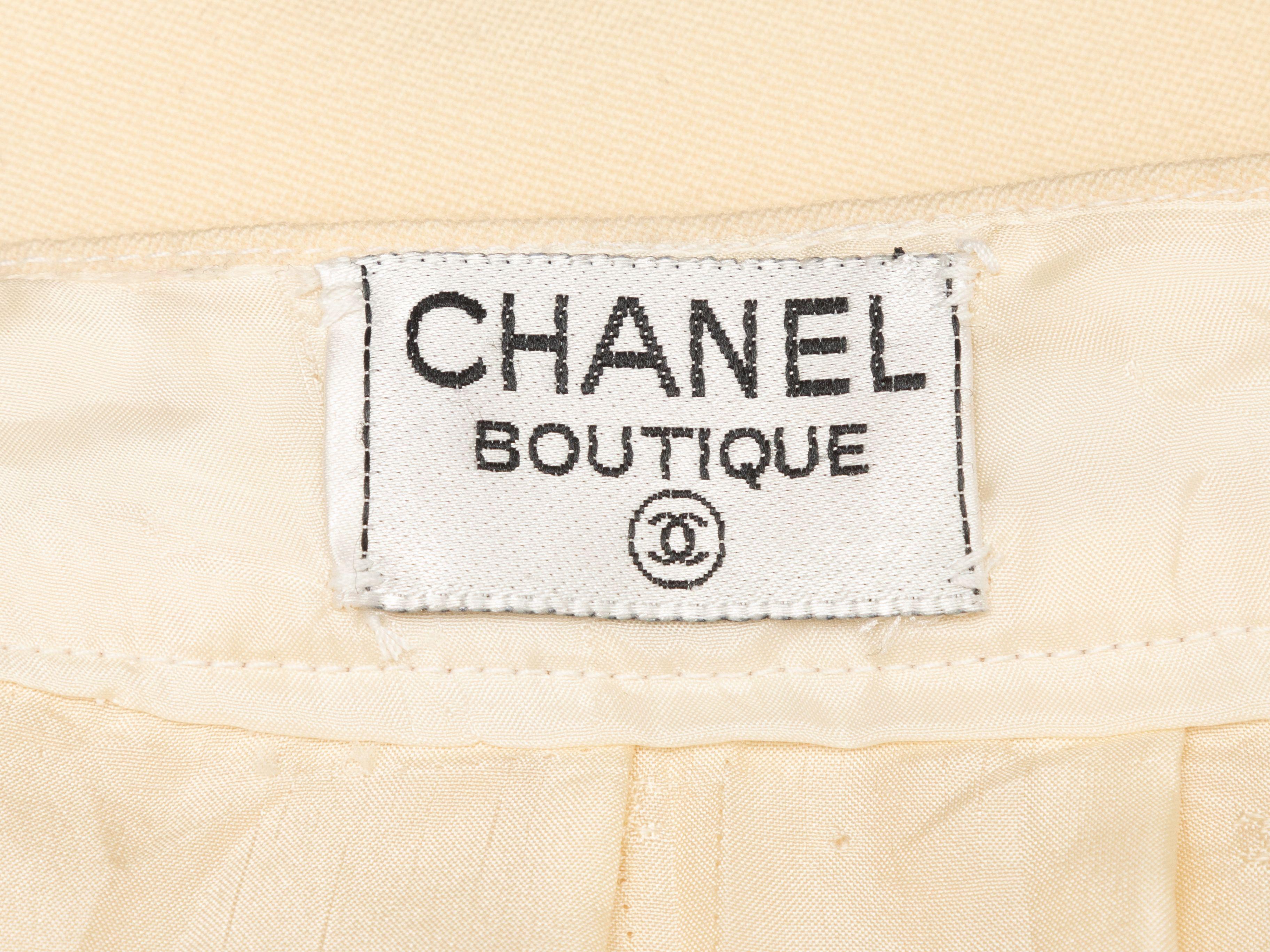 Product Details: Vintage cream wool knee-length pencil skirt by Chanel Boutique. Gold-tone button accents at back hem vent. Zip closure at center back. 26