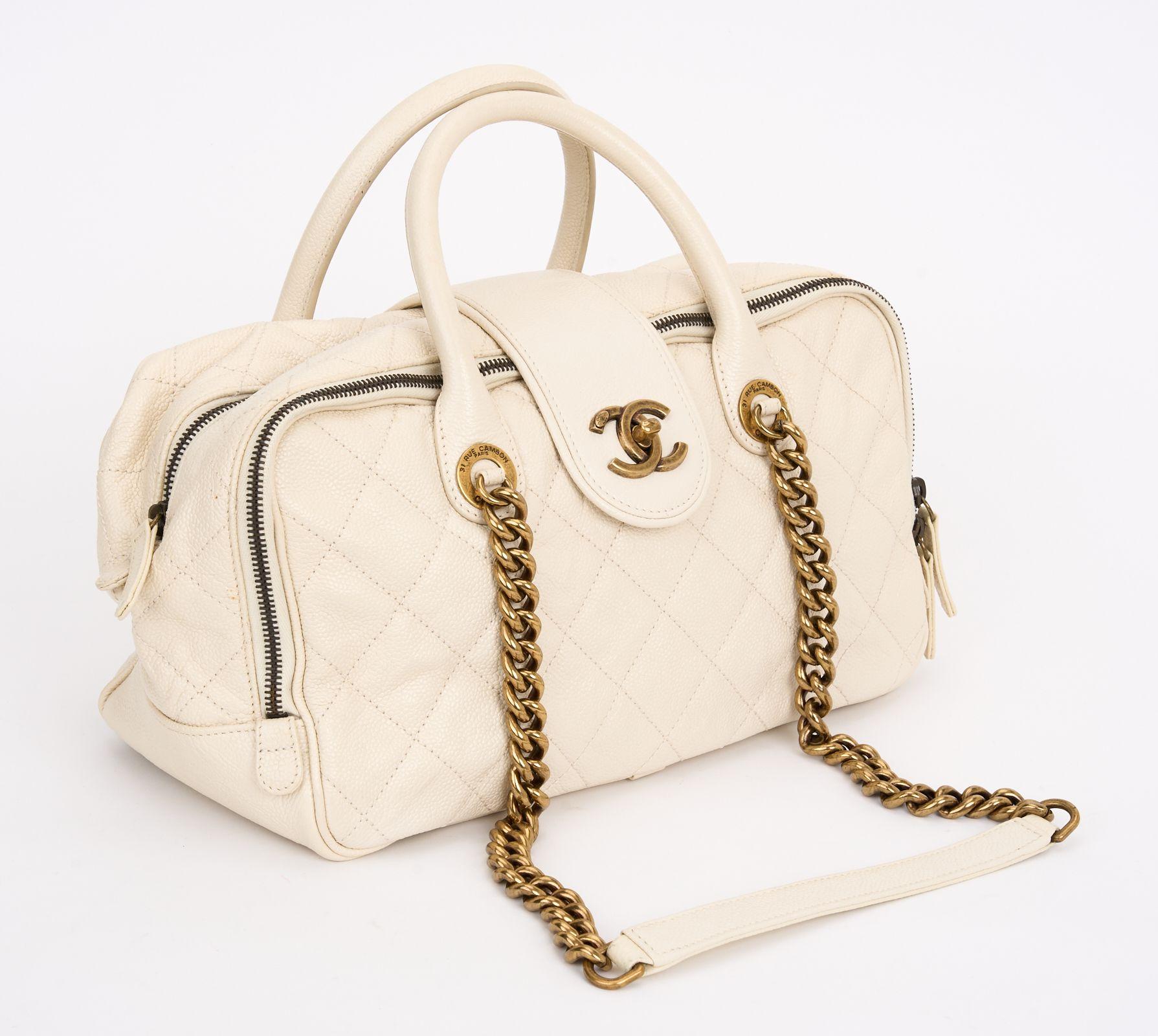 This Chanel Shiva bag from the Bombay collection features crinkled cream caviar-grained leather, bronzed metal hardware, a CC turn lock on the front, rolled leather handles and a burgundy interior. Dust cover included. Hologram first two numbers are