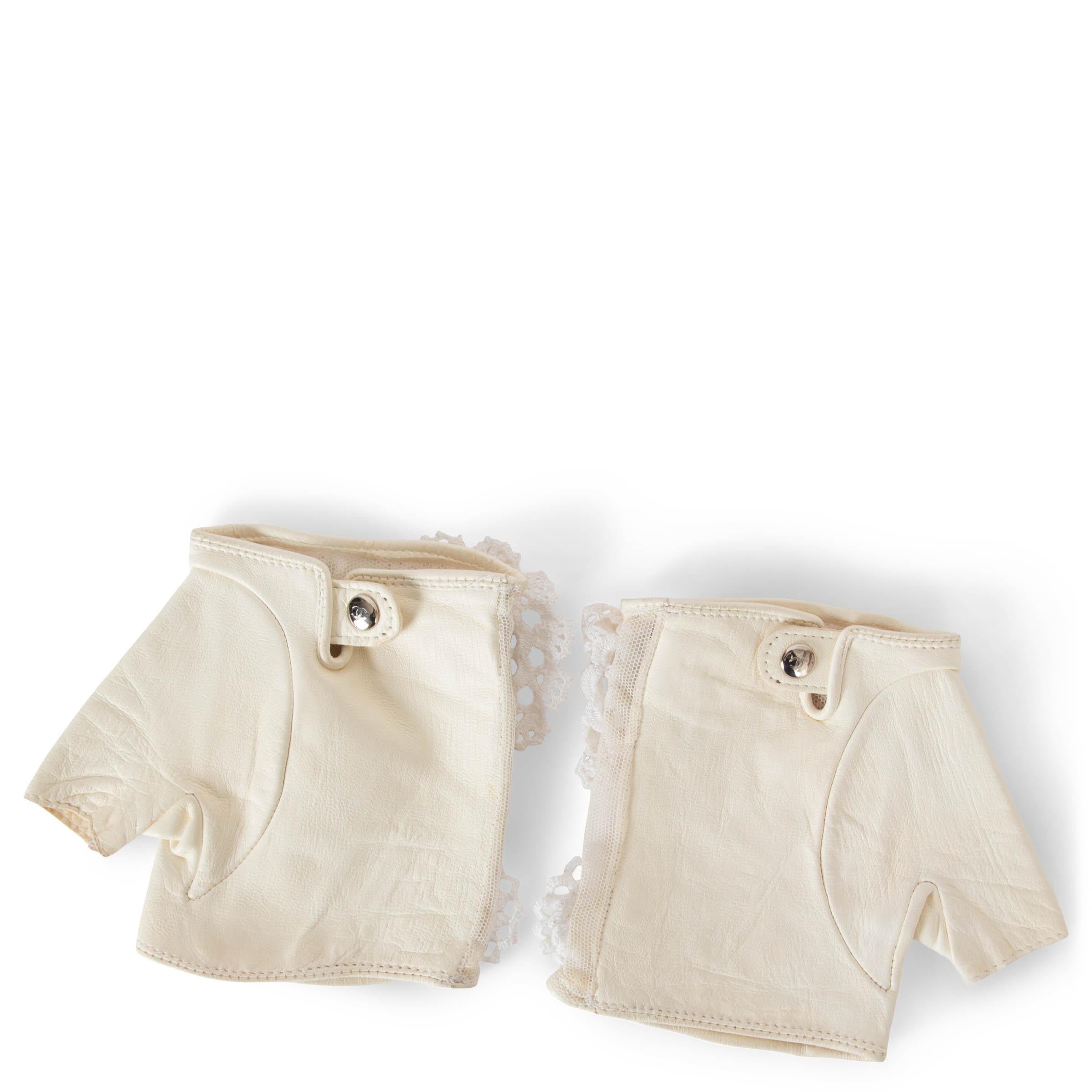 These 100% authentic Chanel fingerless gloves in cream mesh and leather exude delicate elegance with a modern twist. Adorned with intricate floral lace applications and a metal CC logo on the top, they showcase Chanel's signature attention to